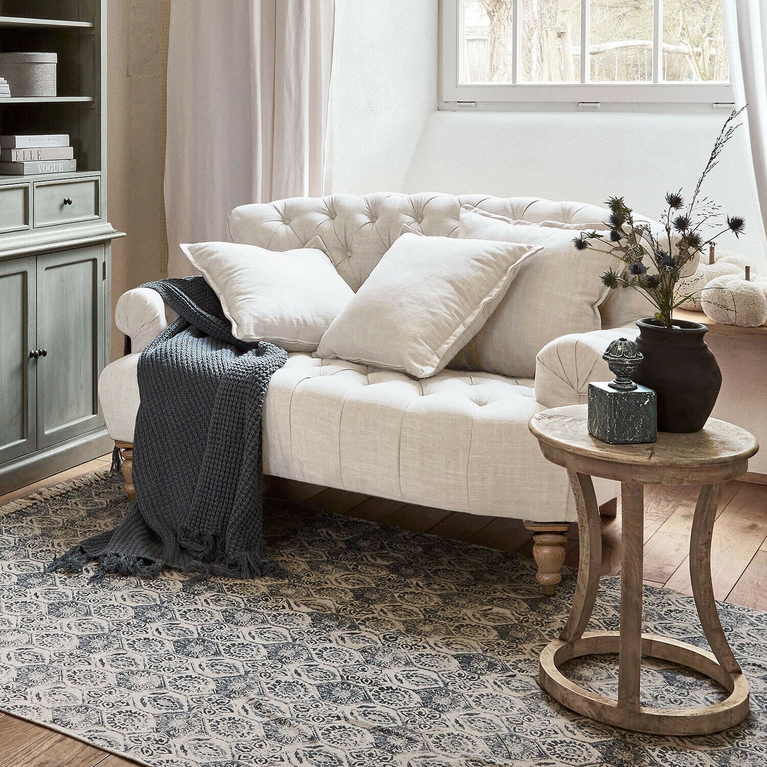 Bank Springfield Village Beige gestoffeerde linnen bank met kussens en grijze gebreide deken in gezellige woonkamer met houten tafel