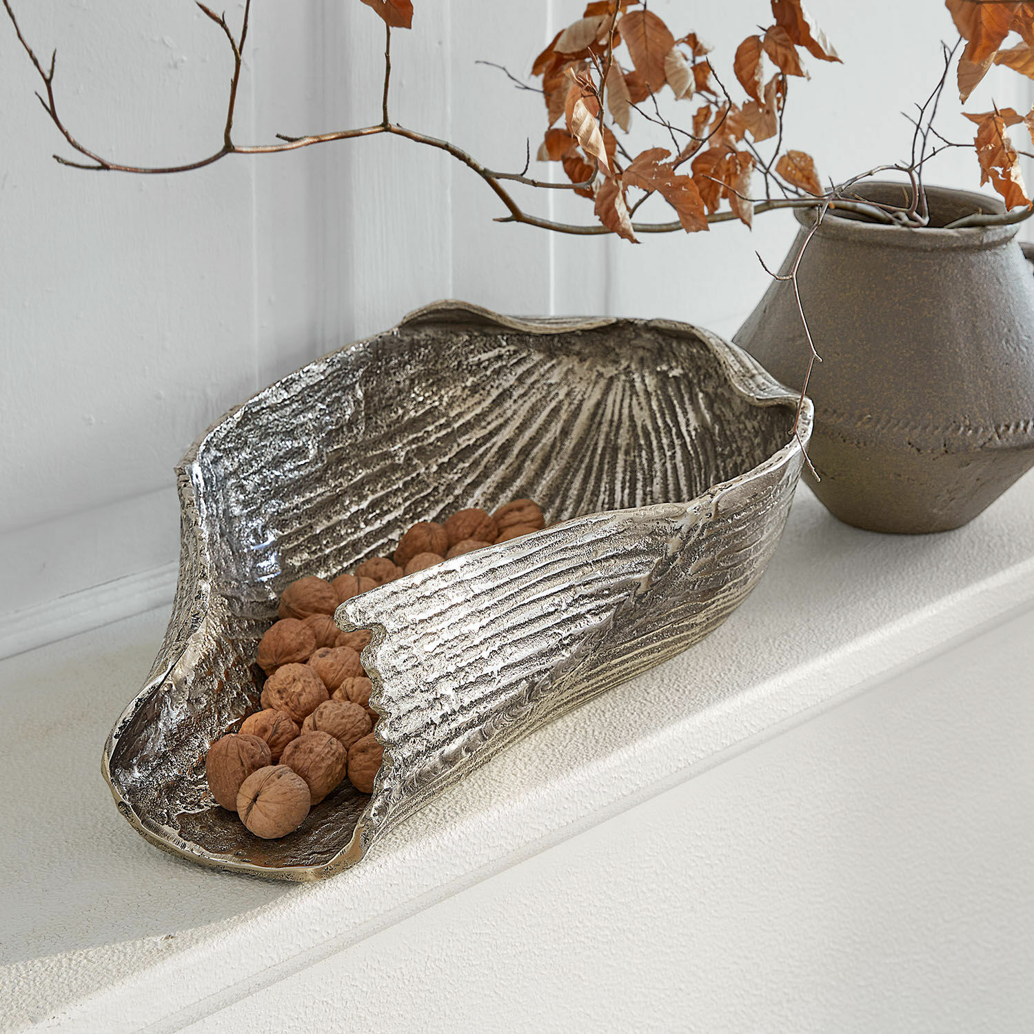 Decoratieve zilverkleurige metalen schaal met walnoten, moderne woonaccessoire