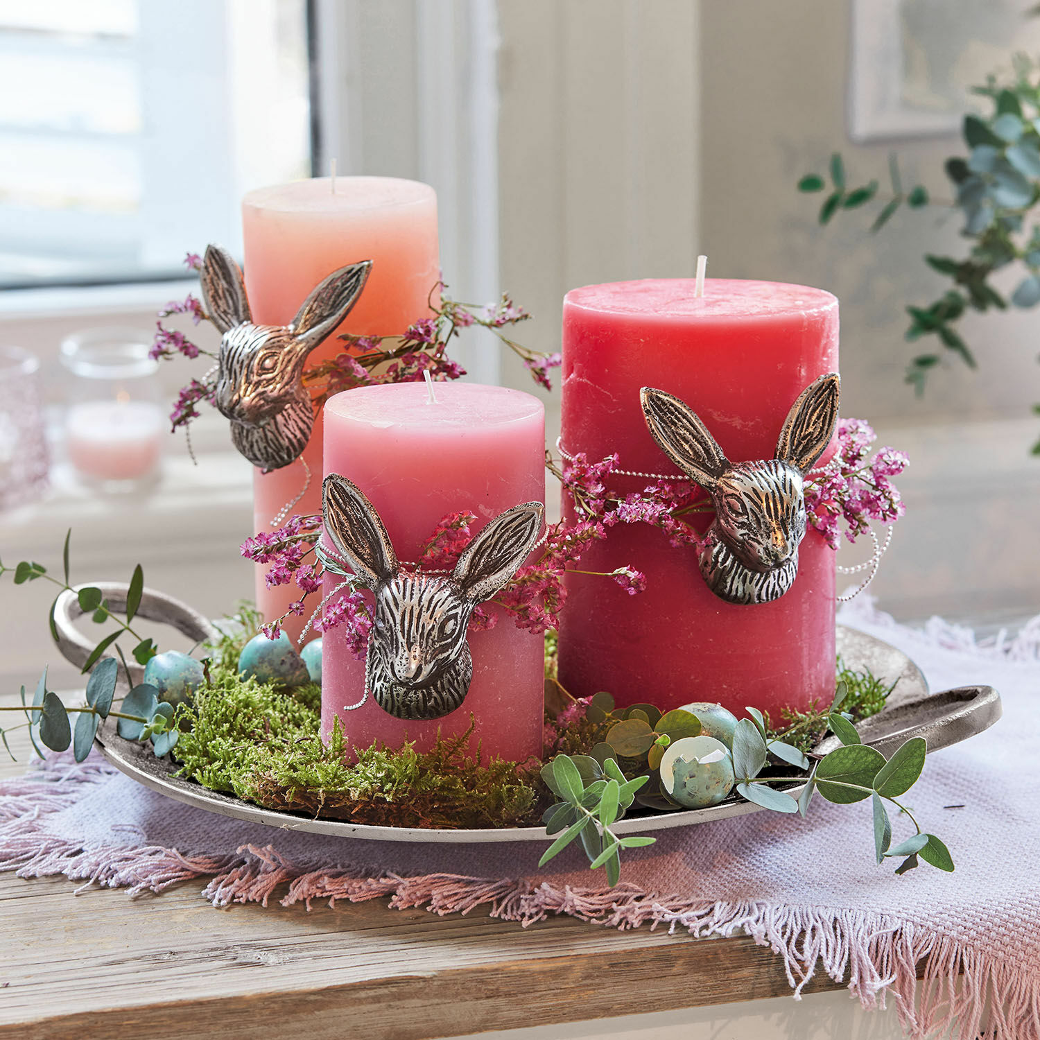 Kaars set van 3 Pretin Set van drie roze kaarsen met konijnenhoofdversiering en groen mos op een metalen dienblad