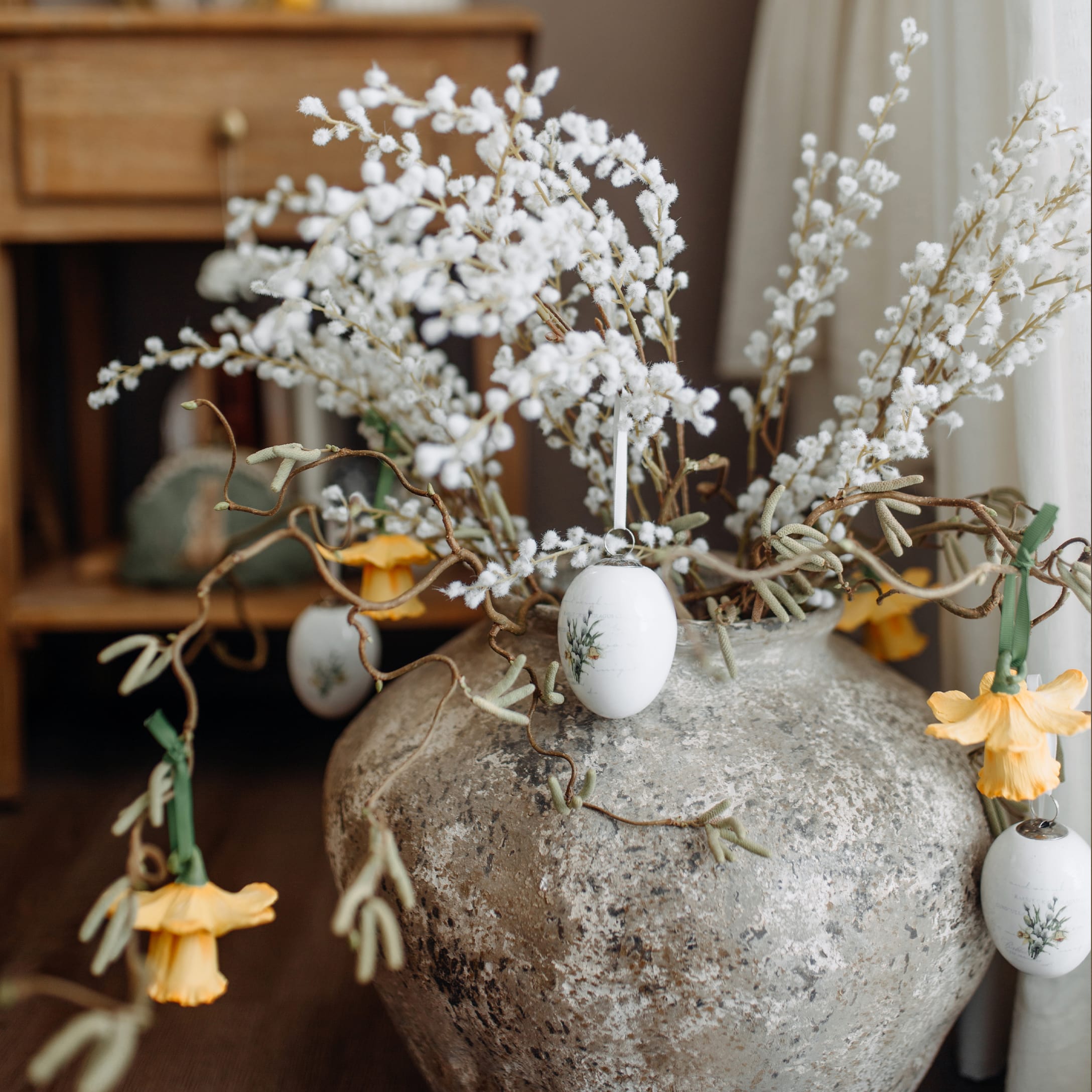 Grijze keramische vaas met witte takken en gele bloemen voor lente- en interieurdecoratie