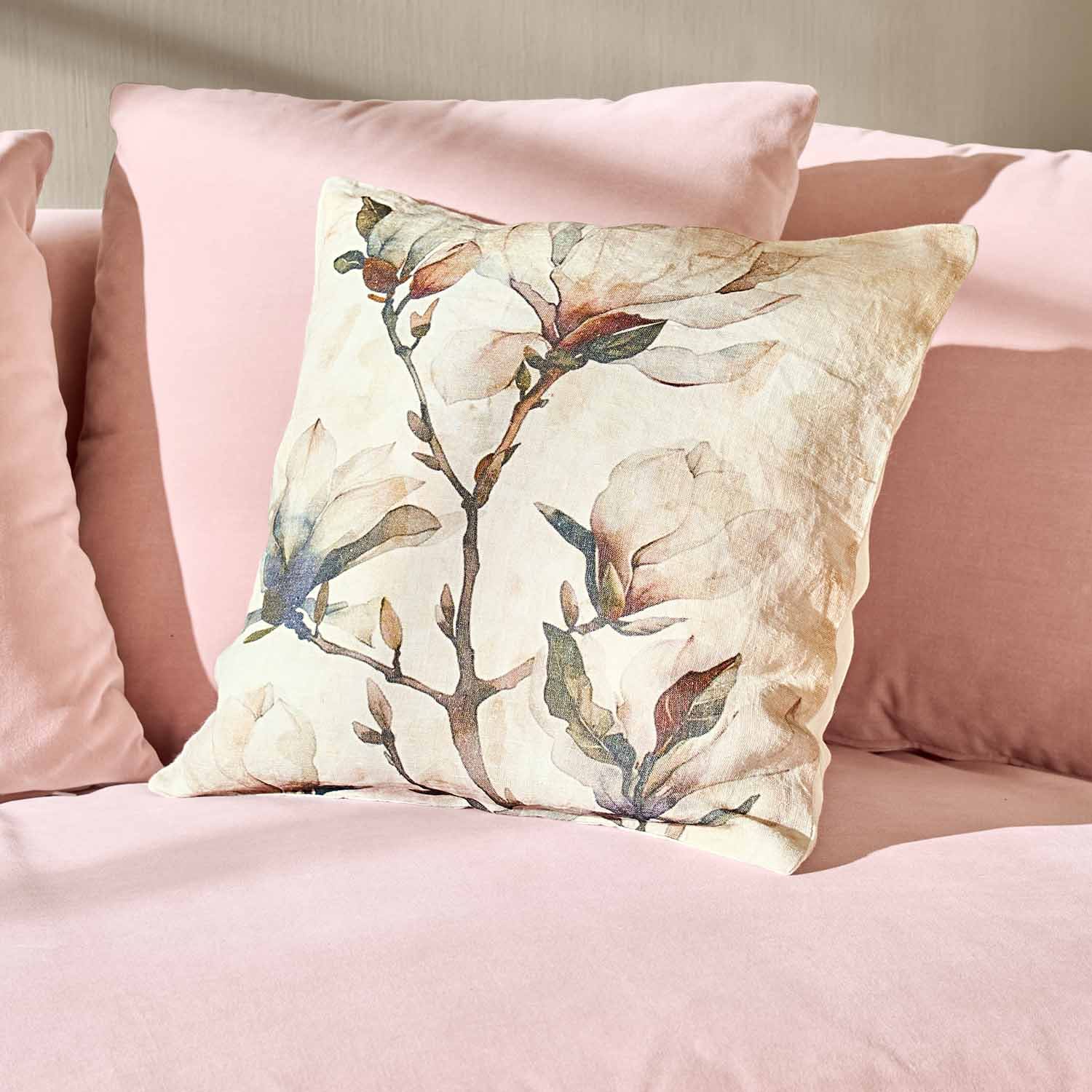 Decoratief katoenen kussen met bloemenprint op roze bank, stijlvolle woonaccessoire