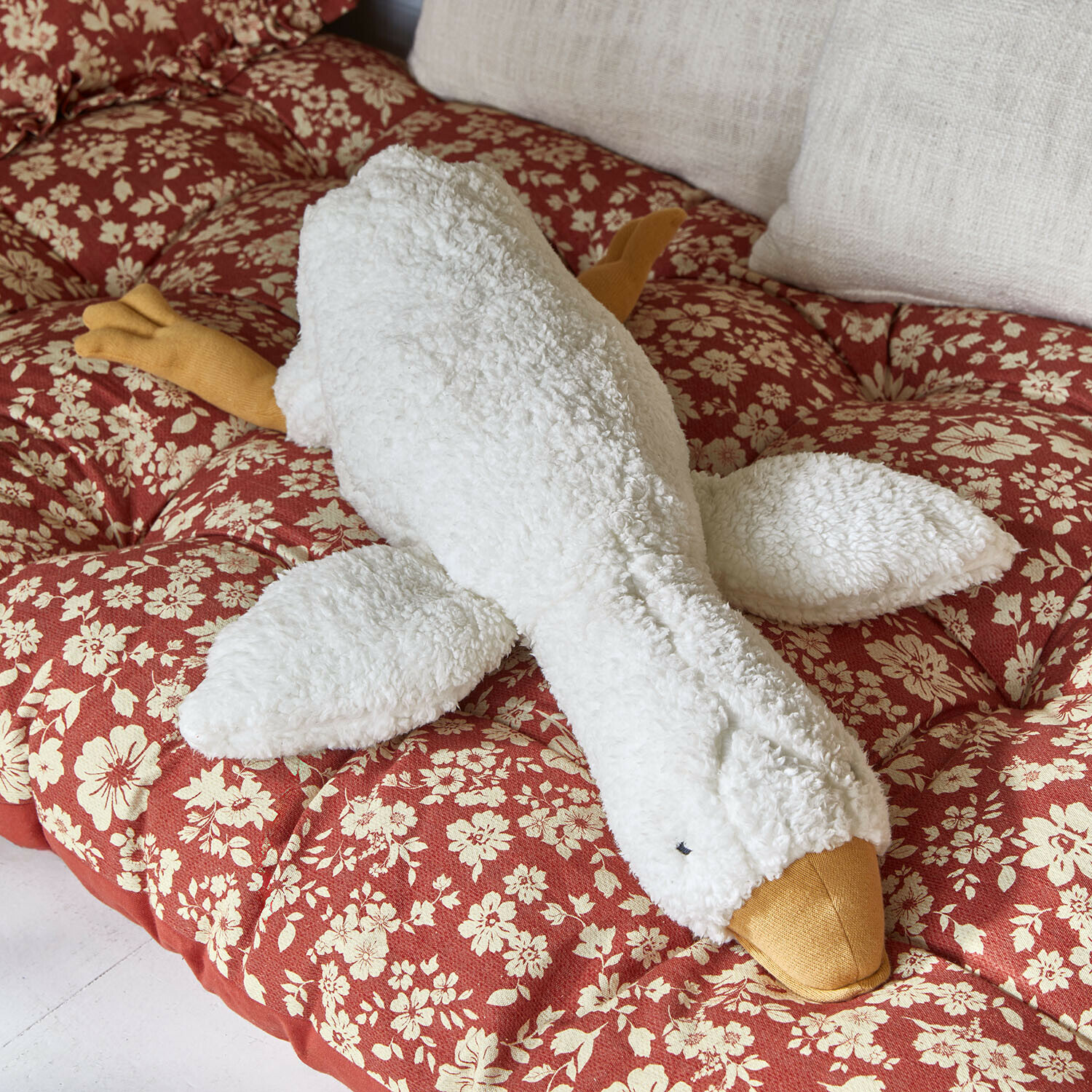 Knuffeltje Tillyboo Zachte pluche gans knuffel in wit en geel op een rood kussen met bloemenpatroon