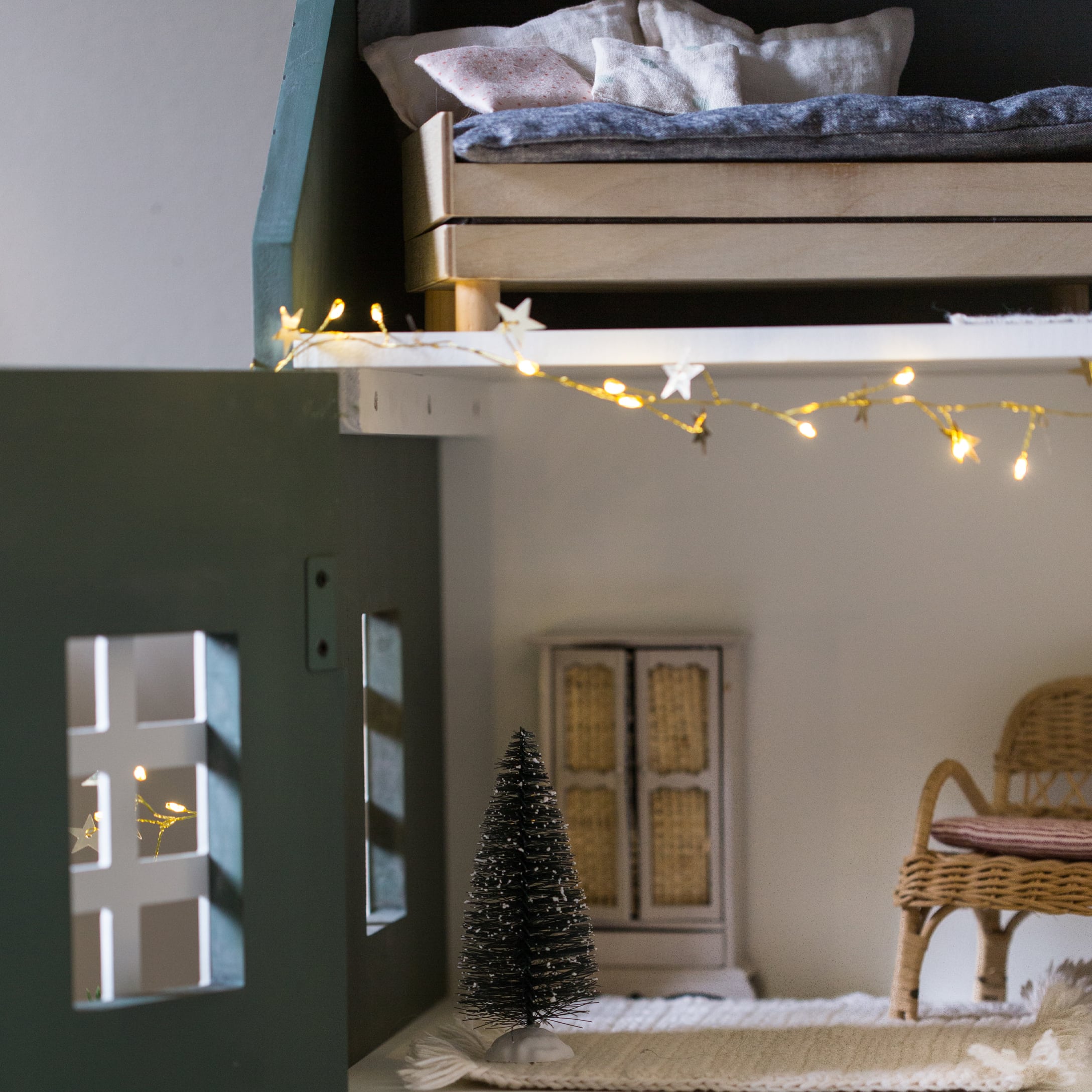 Kleine zwarte decoratieve vezelkerstboom op wit tapijt in gezellige kinderkamer met lichtsnoer