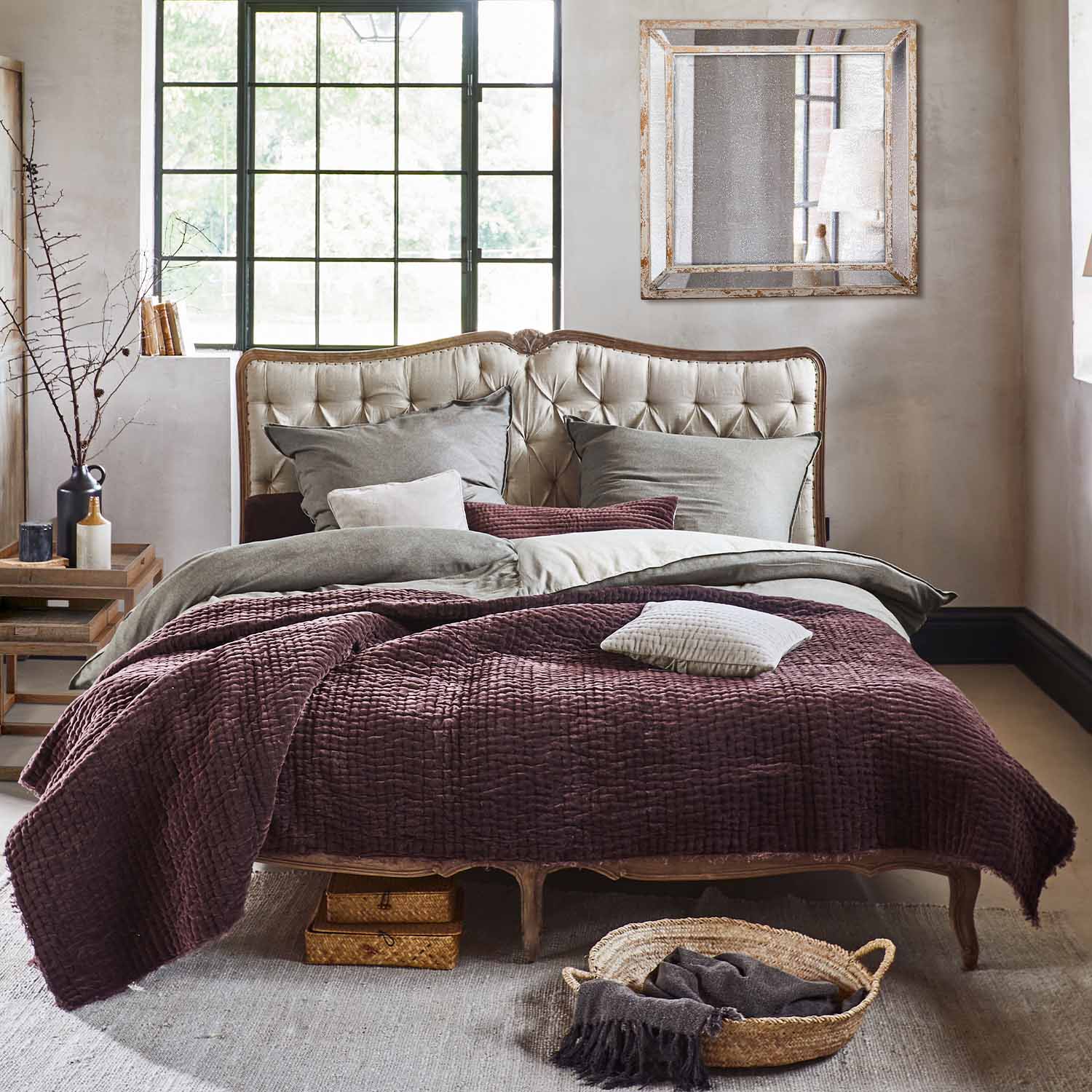 Bed met beige gestoffeerd hoofdeinde en bordeauxrode zachte deken in vintage stijl