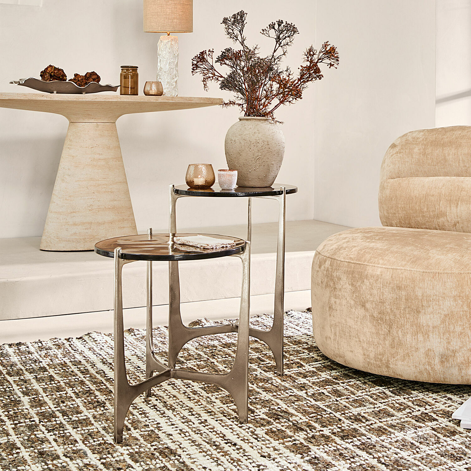 Set van twee bijzettafels met metalen frame en donker blad op tapijt in woonkamer