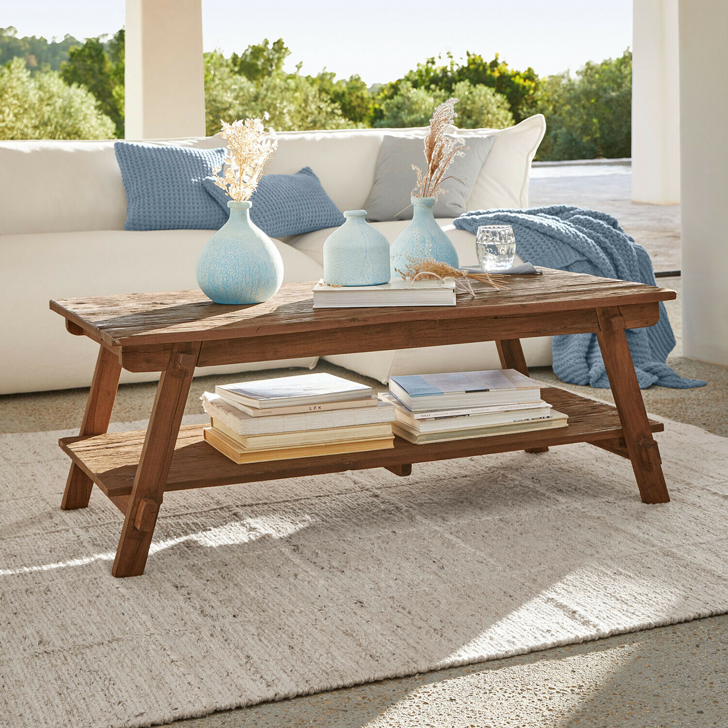 Salontafel van mangohout in natuurlijke kleur met plank, versierd met blauwe vazen en boeken