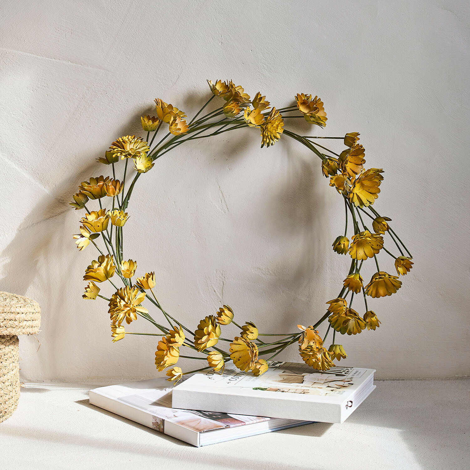 Decoratieve krans van gele metalen bloemen op boeken, interieurdecoratie