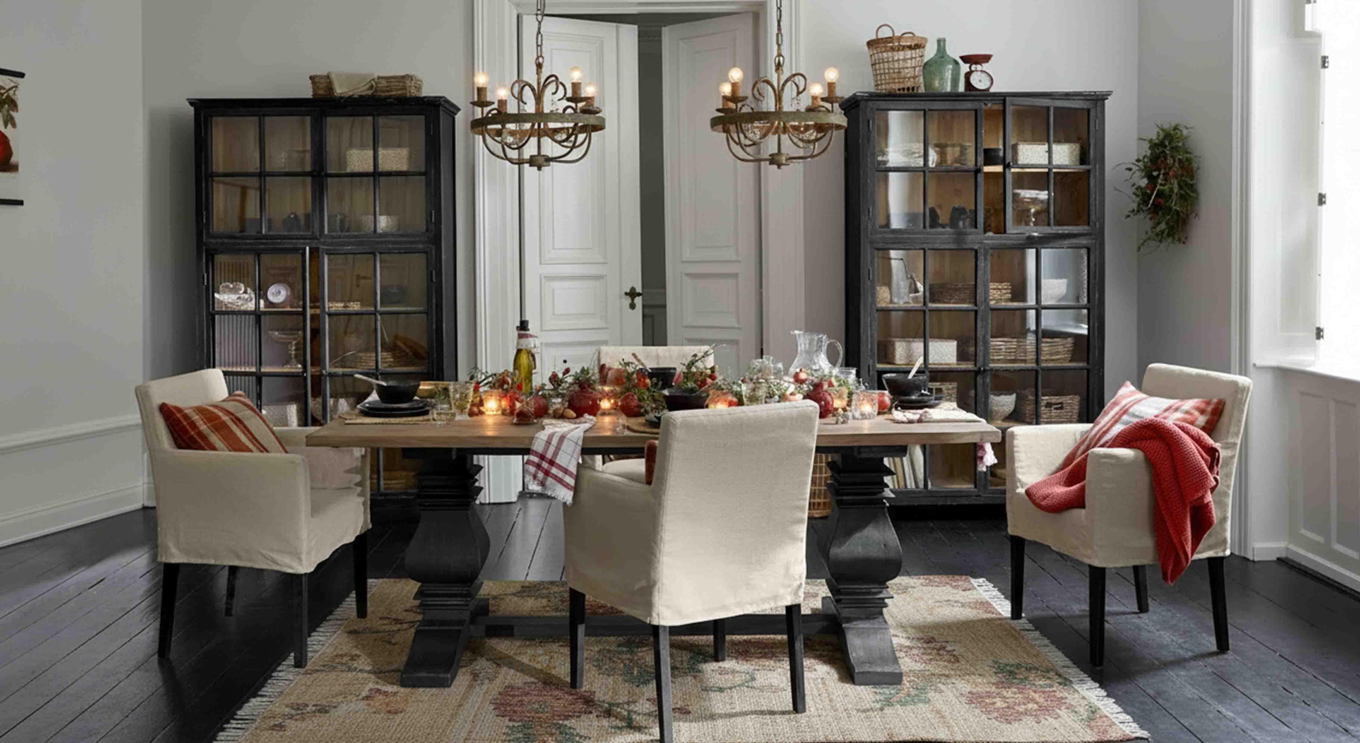 Eetkamer met houten tafel en crèmekleurige stoelen, rustieke decoratie en hanglampen