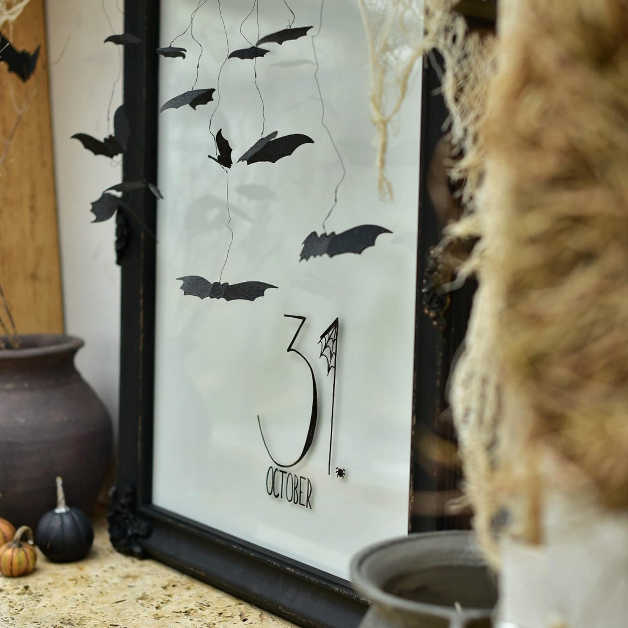 Halloweenversiering met zwarte papieren vleermuizen en tekst 31 oktober in lijst