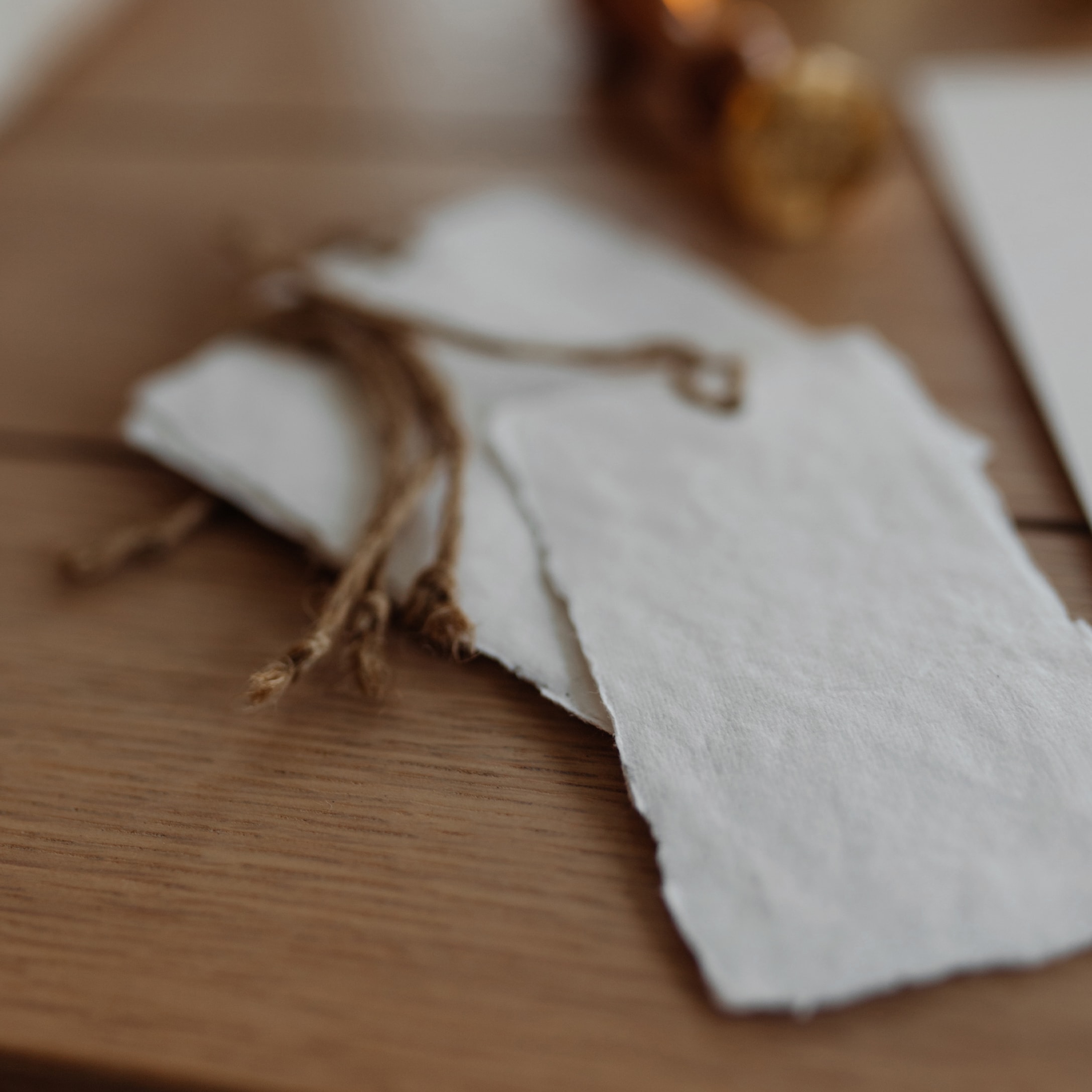 Witte papieren cadeaulabels met natuurlijke touw op houten tafel