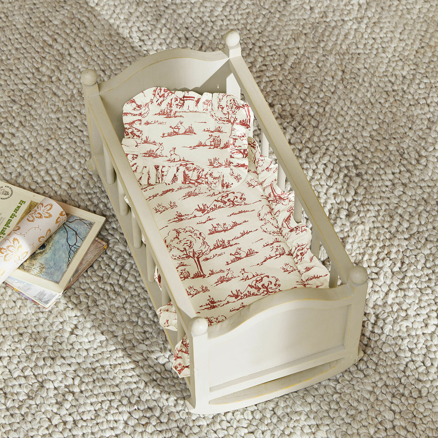Beddengoed voor poppen Fleurine Witte houten poppenwieg met matras en rood bedrukt hoeslaken op beige tapijt
