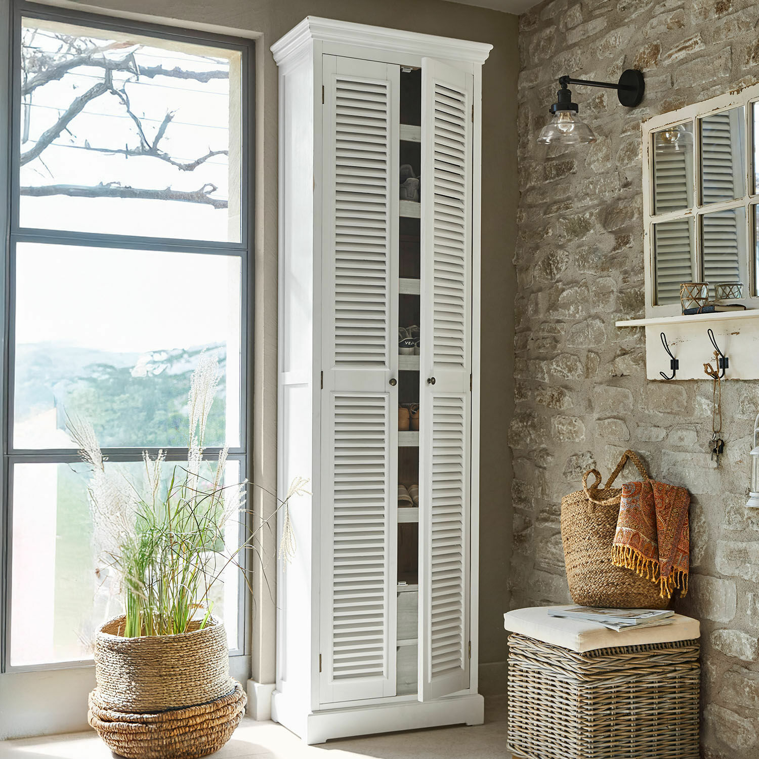 Schoenenkast Blossomby Witte houten kast met luikdeuren in rustieke kamer met stenen muur en manddecoratie