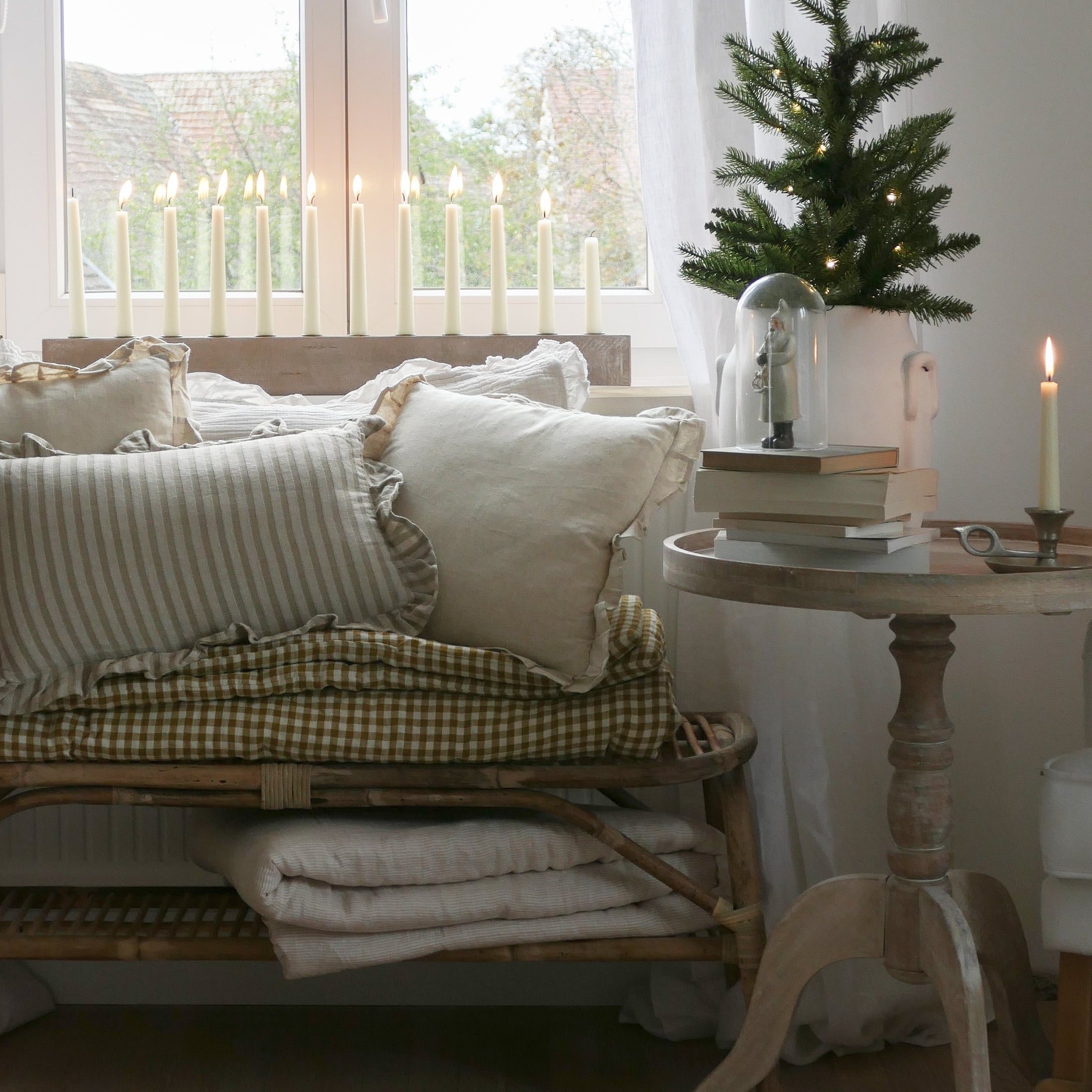 Gezellige hoek met beige kussens en houten tafel met decoraties en brandende kaarsen