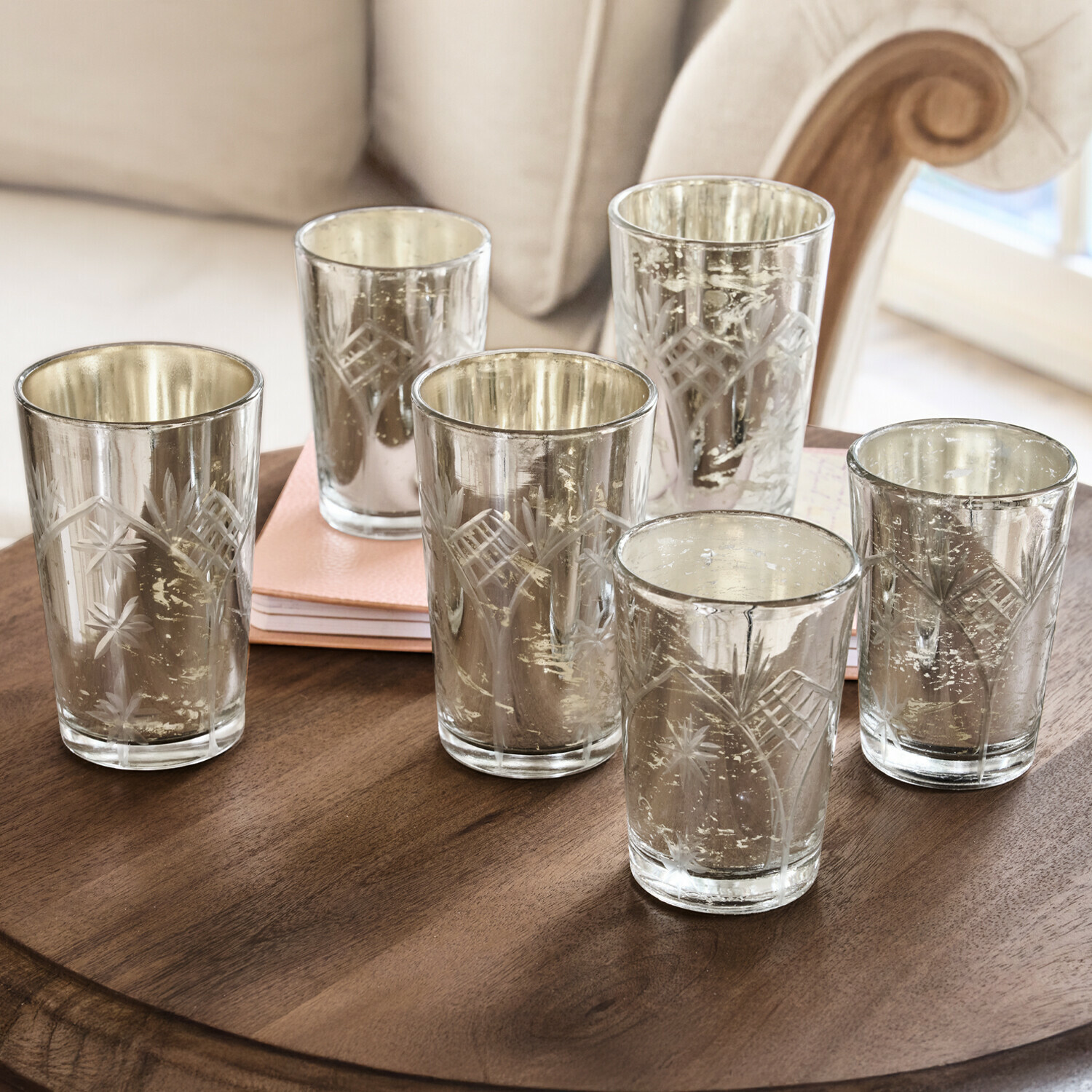Set van zes gegraveerde glazen theelichthouders met zilveren afwerking op houten tafel