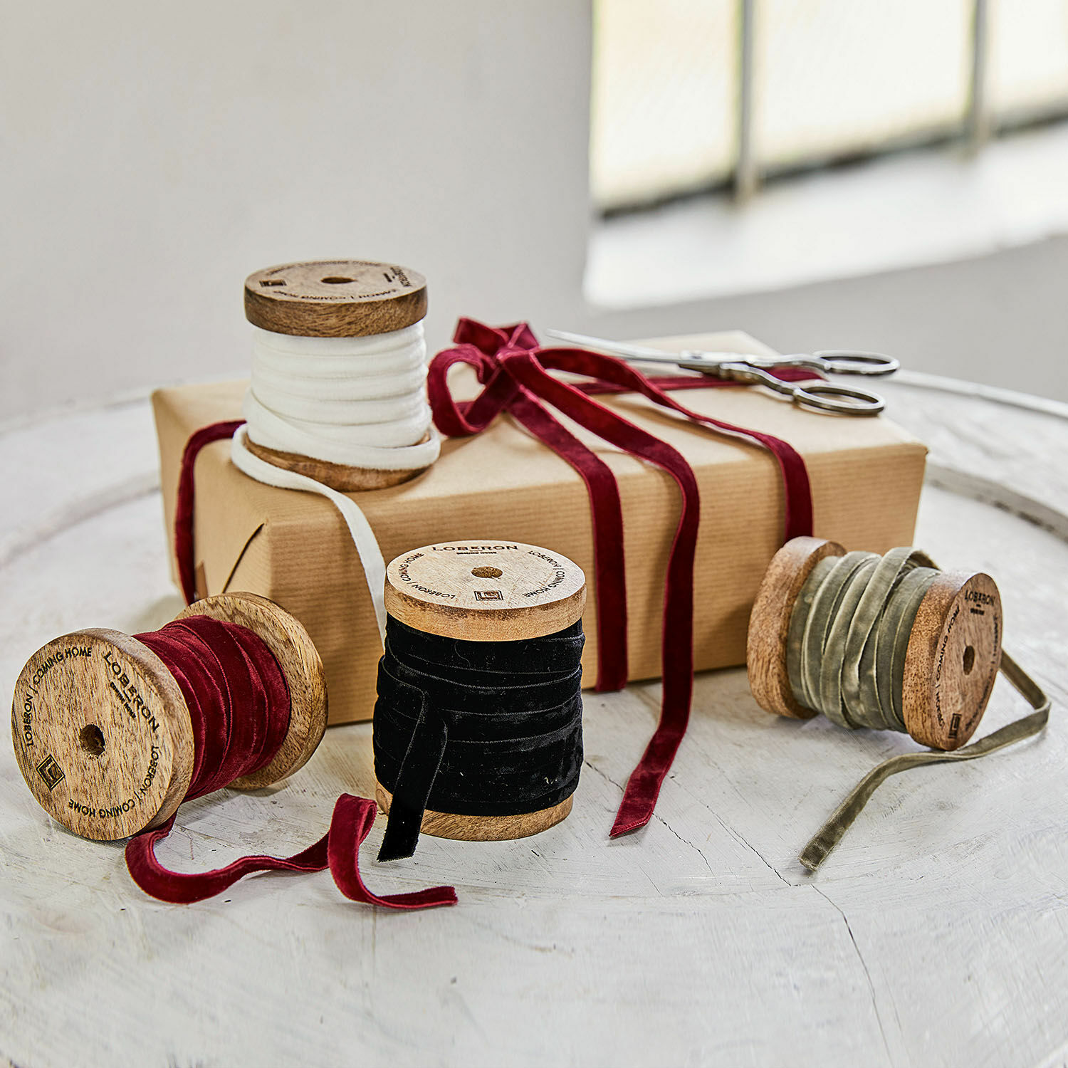 Fluwelen lint set van 4 Hilary Set houten spoelen met fluwelen linten in wit, rood, zwart en olijfgroen op tafel met cadeau
