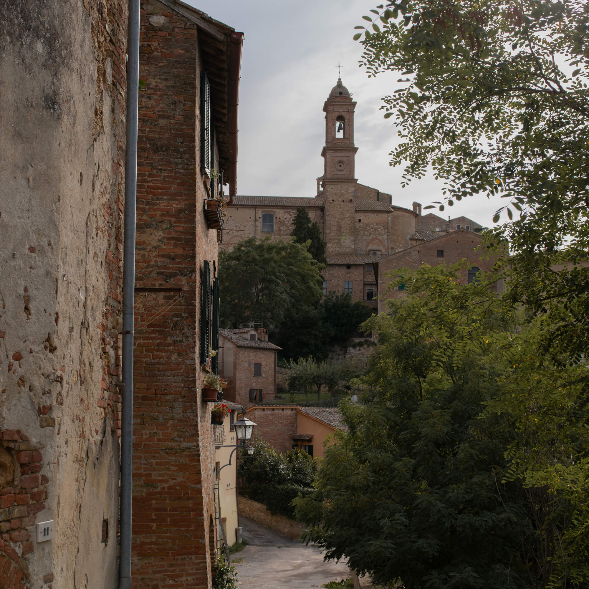 Uitzicht op een oude stenen straat met bakstenen gebouwen en kerkklokketoren op de achtergrond