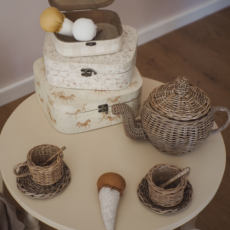Kinder theeservies van gevlochten riet met theepot en kopjes op een ronde tafel