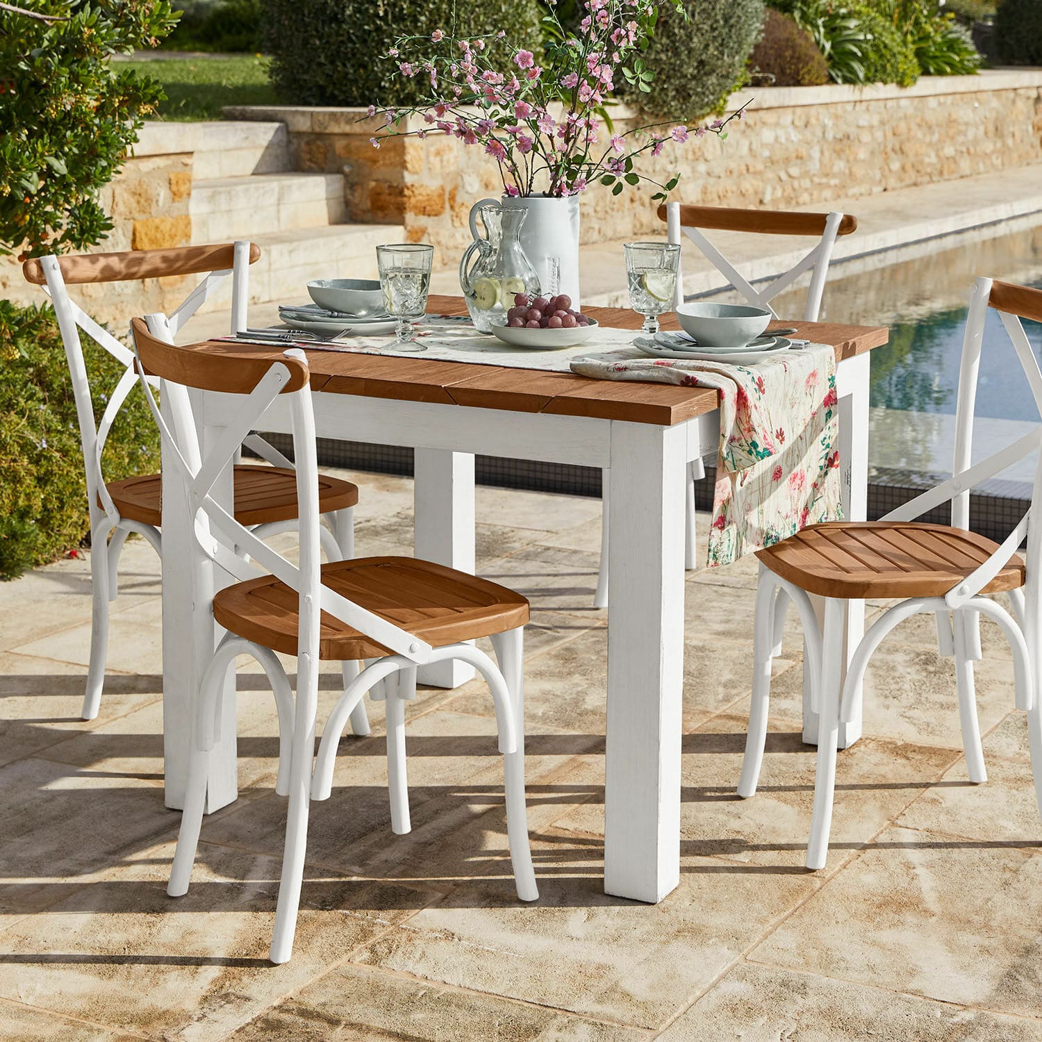 Tafel Kirkdale Tuinmeubelset met witte houten tafel en stoelen met houten zittingen op stenen terras