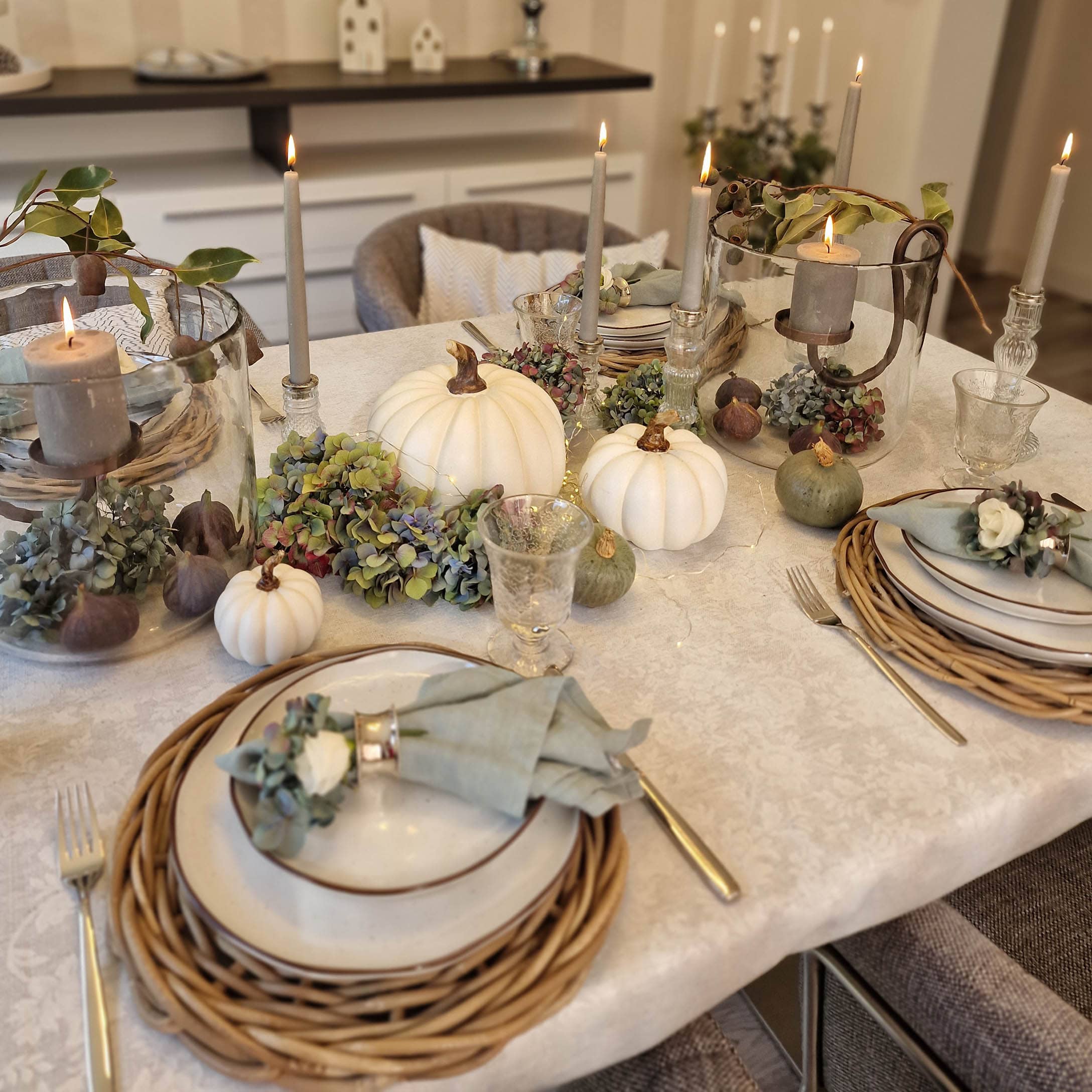 Elegante herfsttafeldecoratie met witte pompoenen, kaarsen en natuurlijke accenten op tafelkleed