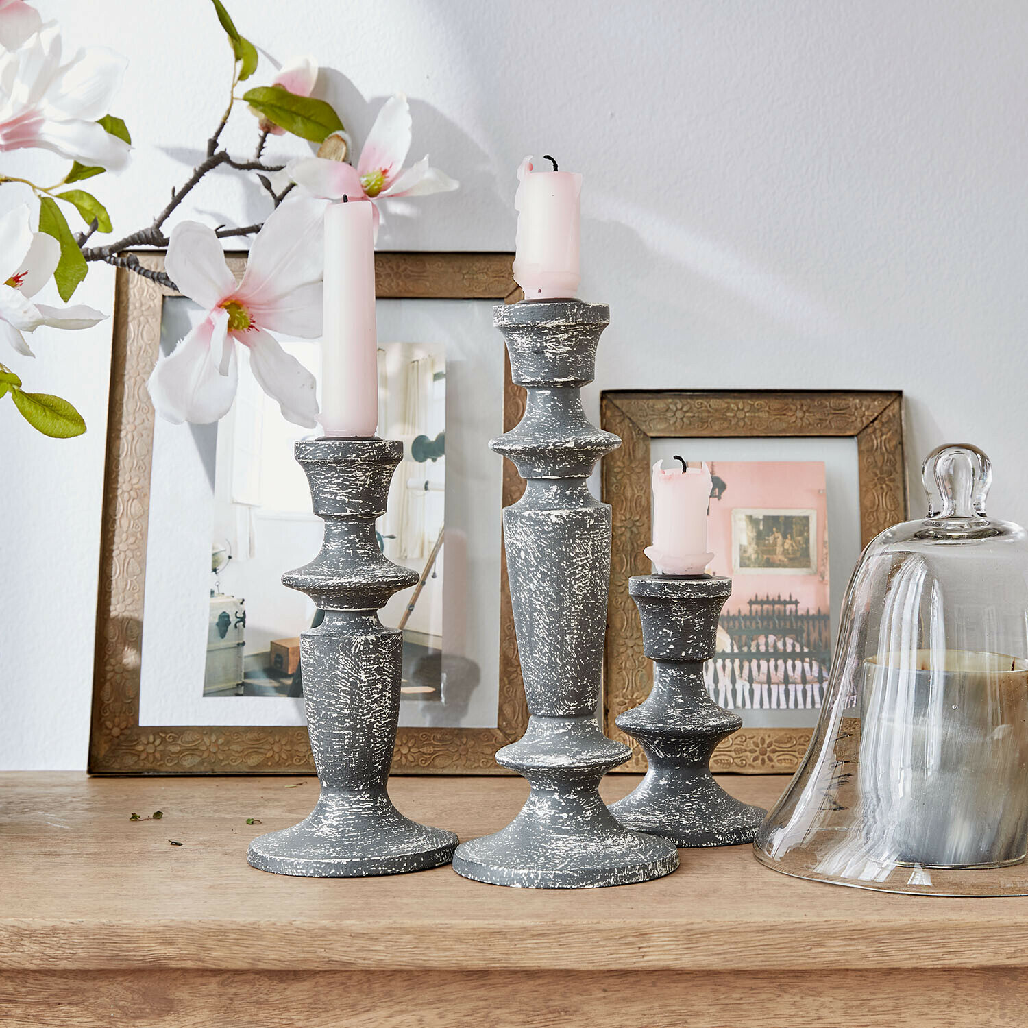 Set van drie grijze kaarsenhouders van verouderd hout met roze kaarsen op houten tafel