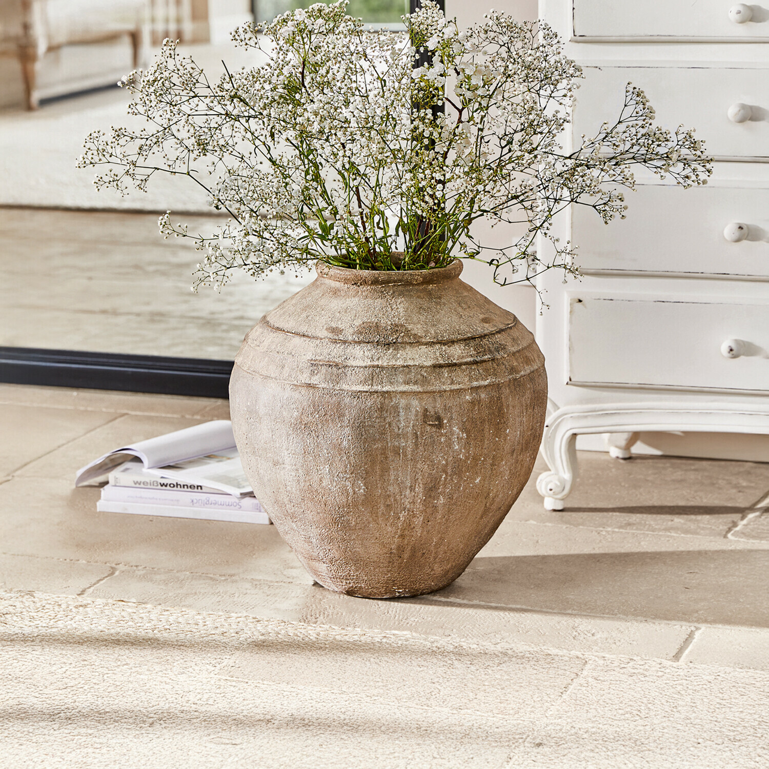 Grote beige keramische vaas met fijne witte bloemen voor stijlvolle interieurdecoratie