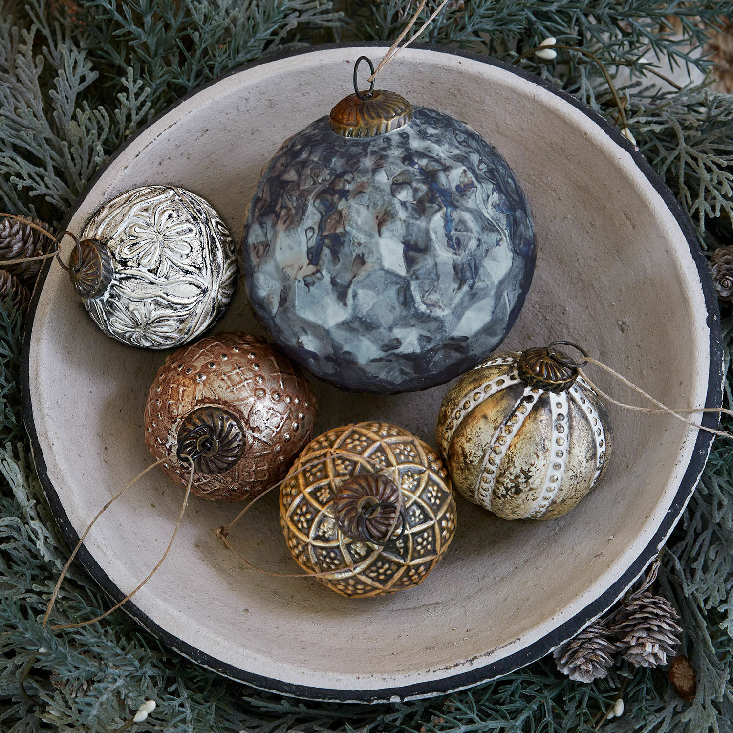 Kerstversiering set van 5 Jilian Decoratieve metalen kerstballen in verschillende kleuren in een keramische schaal op groene achtergrond