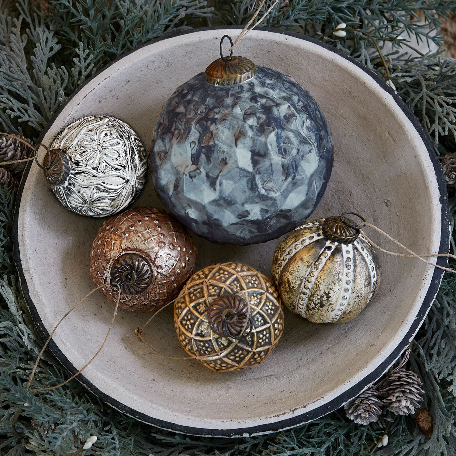 Kerstversiering set van 5 Jilian Decoratieve metalen kerstballen in verschillende kleuren in een keramische schaal op groene achtergrond