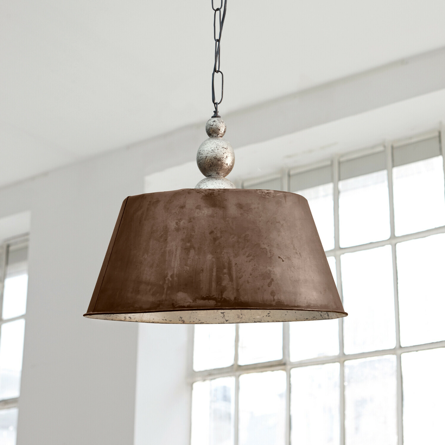 Hanglamp Chatel Twee messingkleurige metalen hanglampen boven lichte eettafel met decoratie en servies