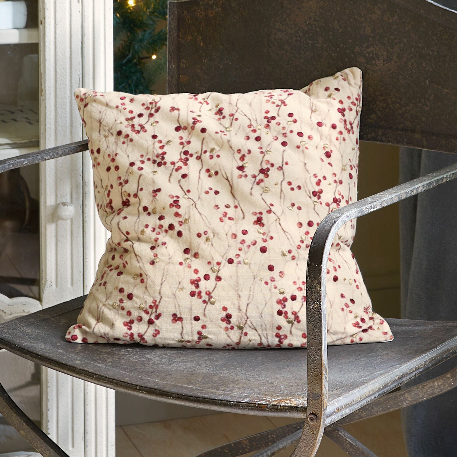 Kussenhoes Rimont Beige sierkussen met rode patronen op een metalen vintage stoel voor interieurdecoratie