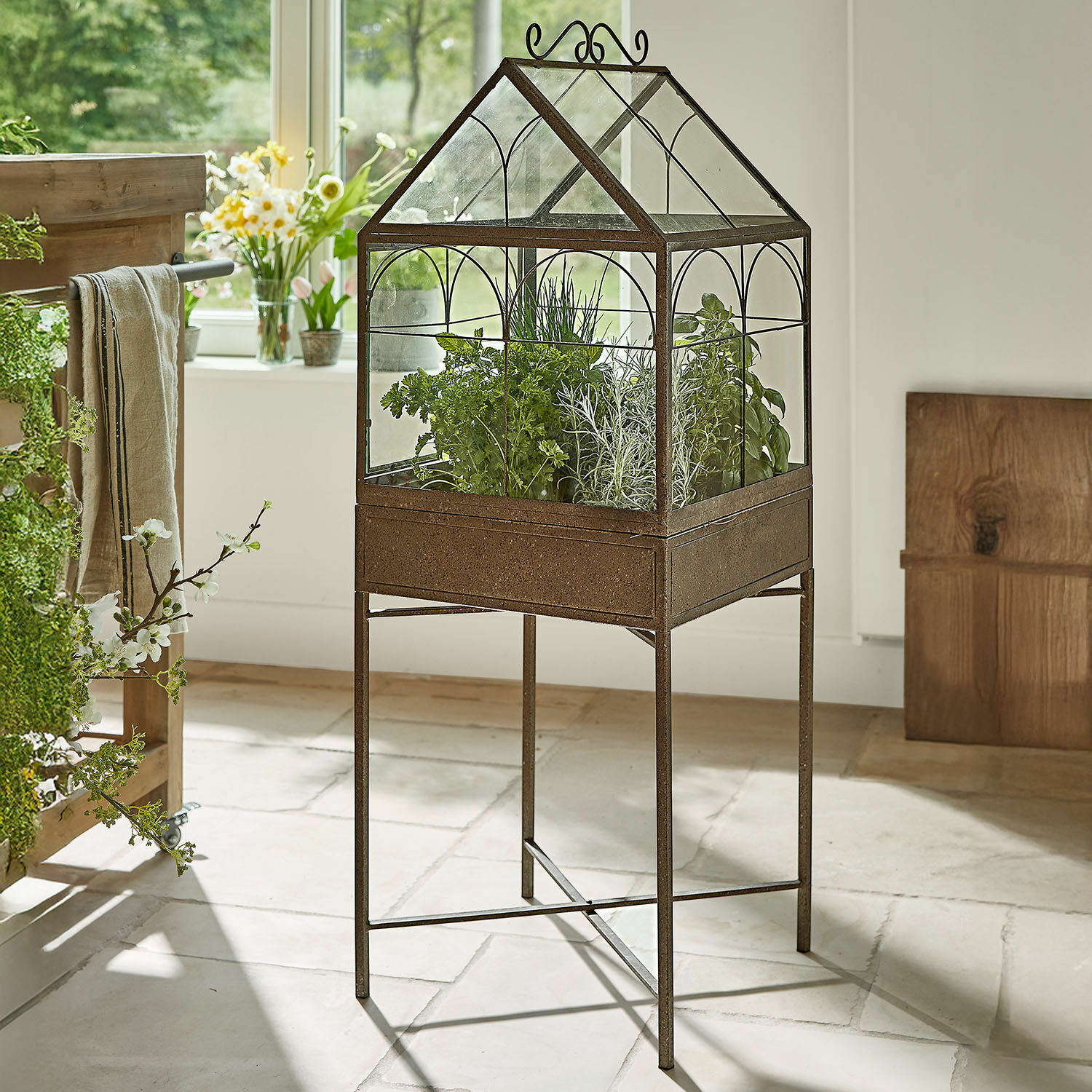 Kweekkas op metalen standaard met roestkleurige afwerking en verse groene kruiden voor binnen