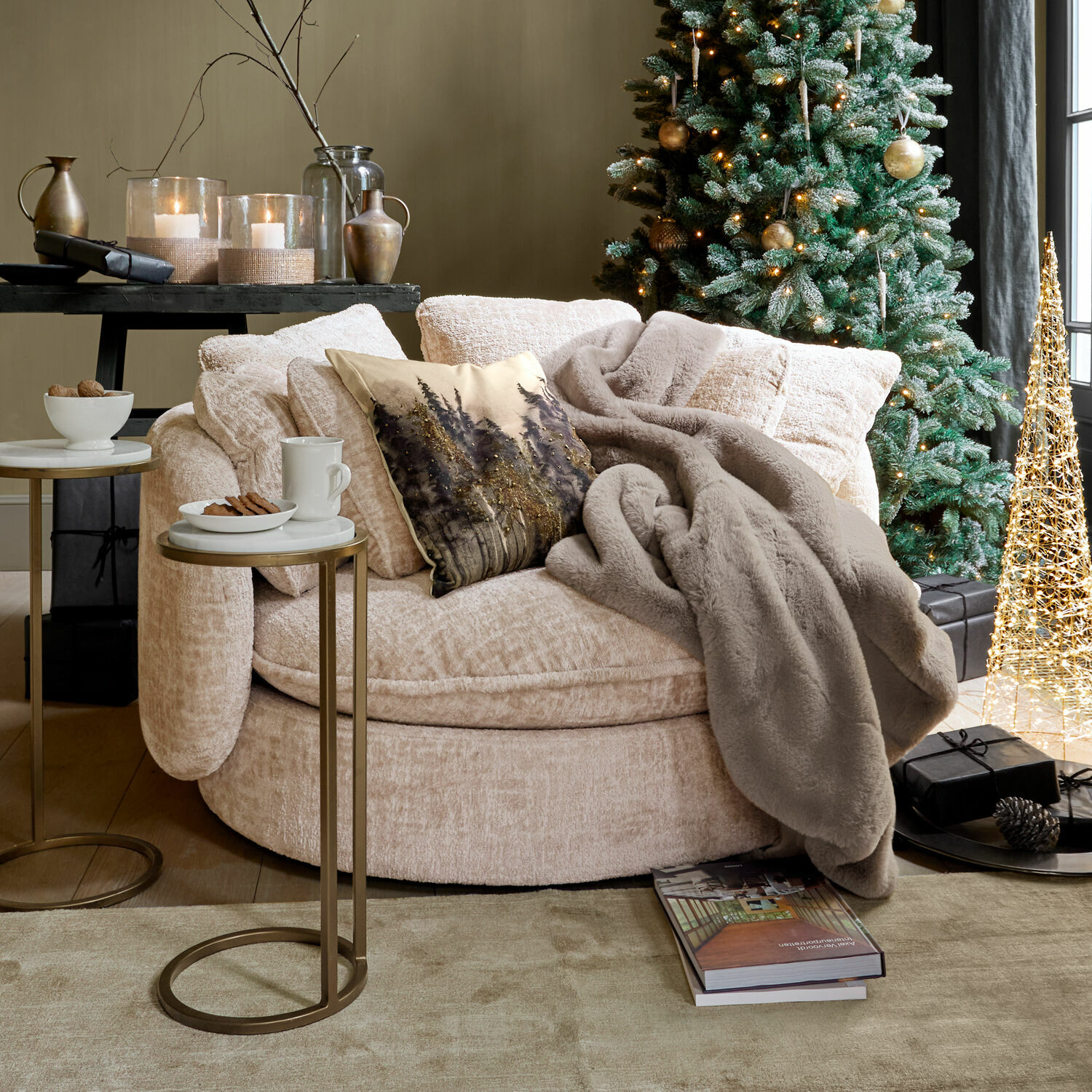 Beige ronde fauteuil van zachte stof met grijze deken bij versierde kerstboom en cadeaus