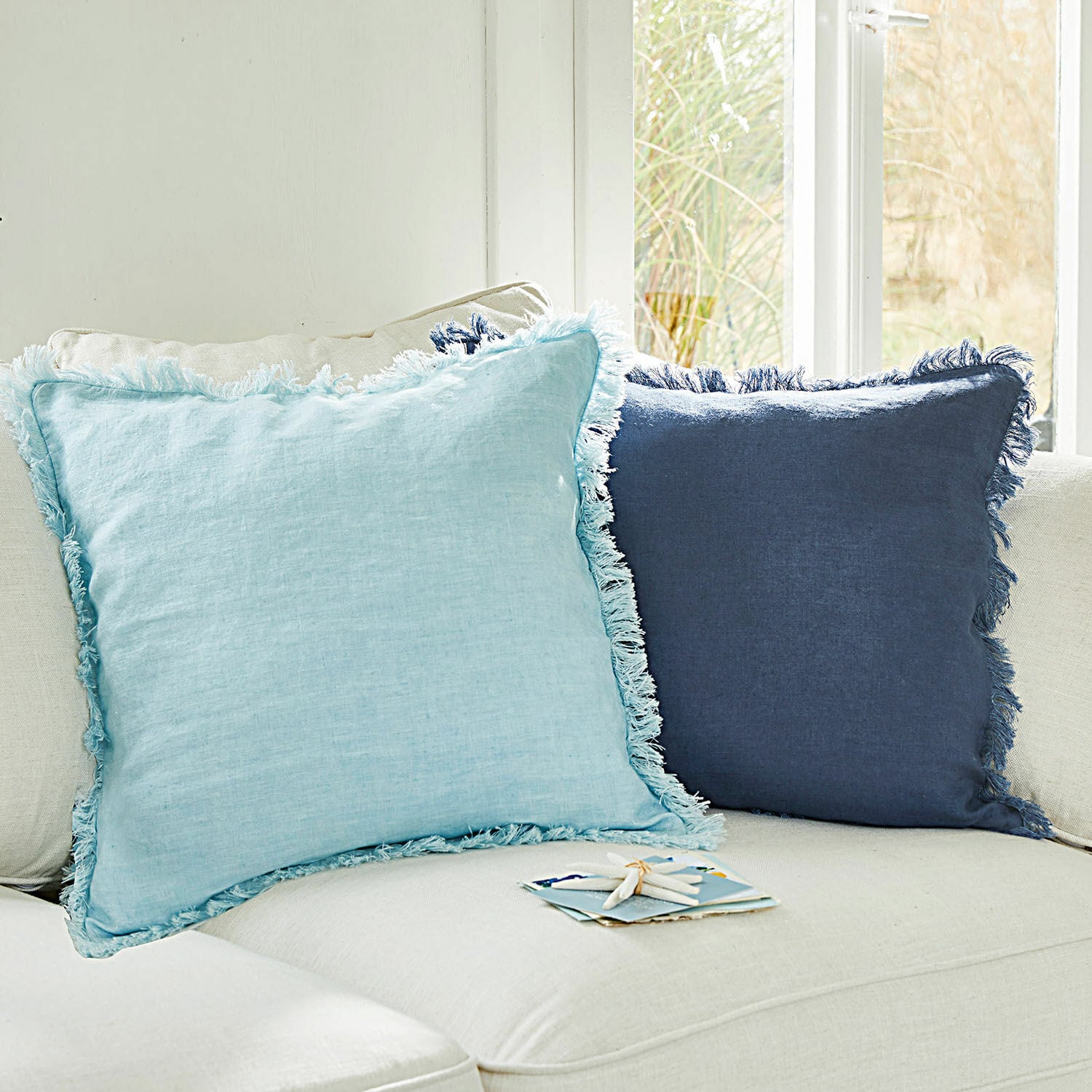 Kussenhoes set van 2 Quebo Set van twee decoratieve linnen kussens in lichtblauw en donkerblauw met franjes op een lichte bank