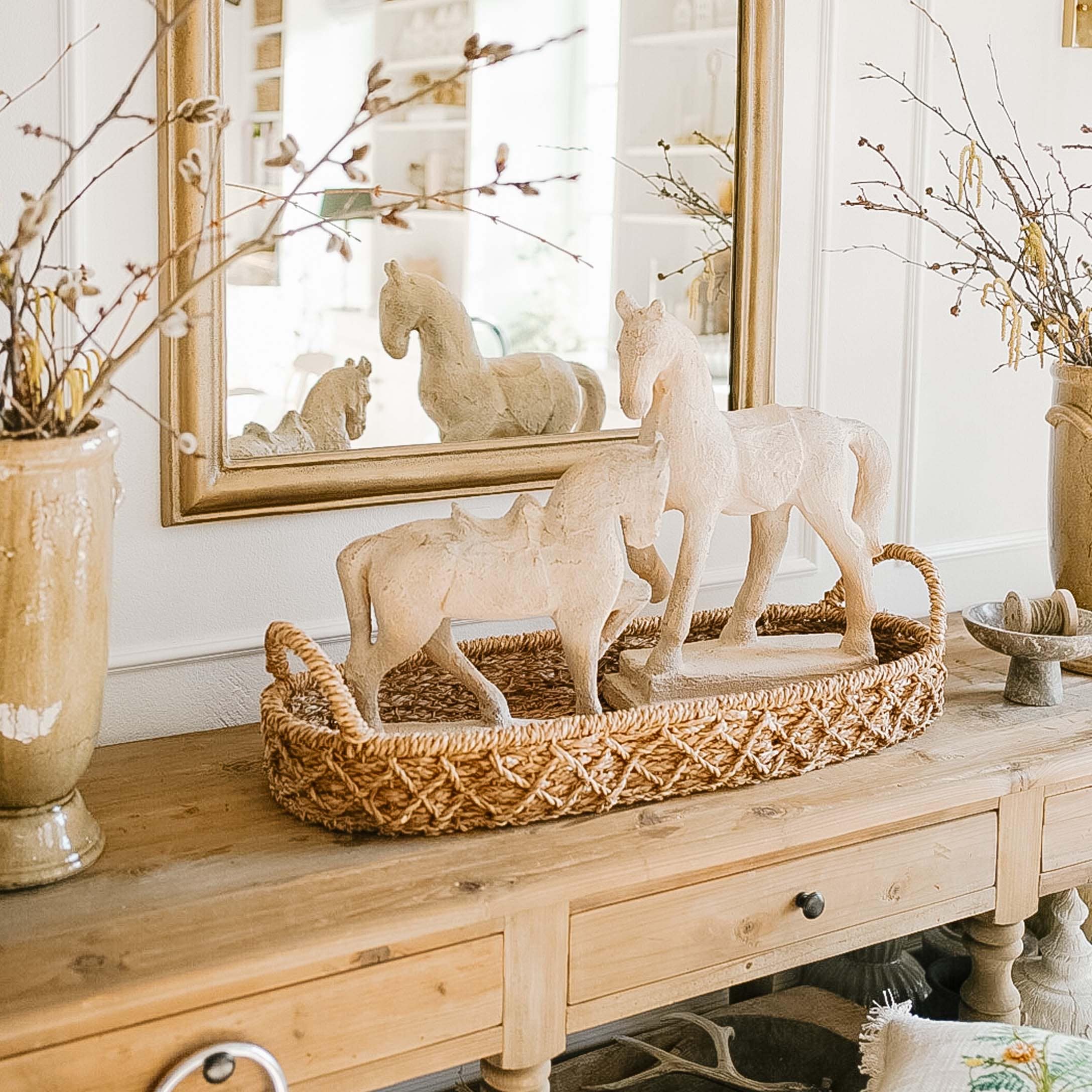Witte paardenfiguren van materiaal op gevlochten bruine schaal op houten tafel decoratief
