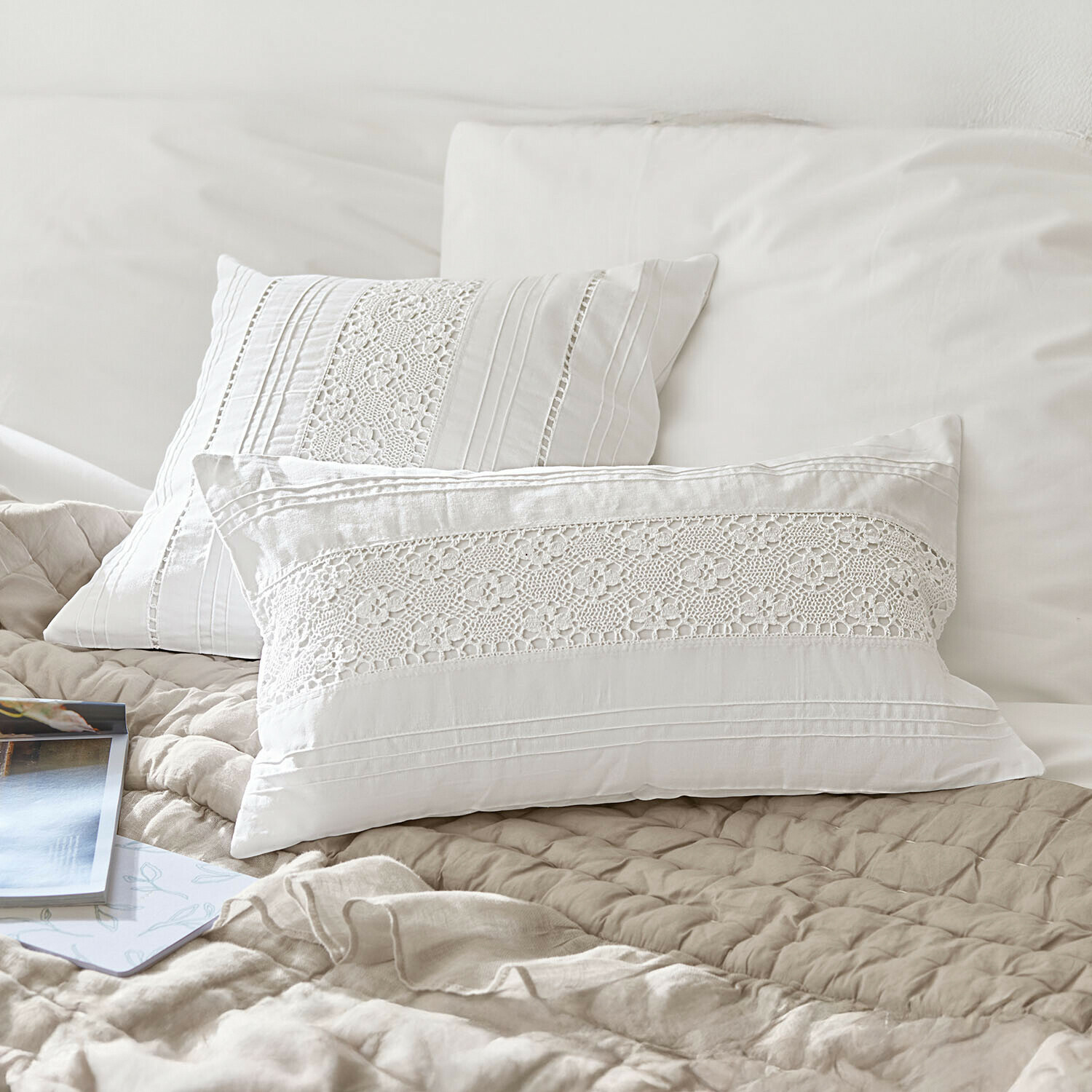 Witte katoenen kussens met kantpatroon op beige quilt, stijlvolle slaapkamerdecoratie