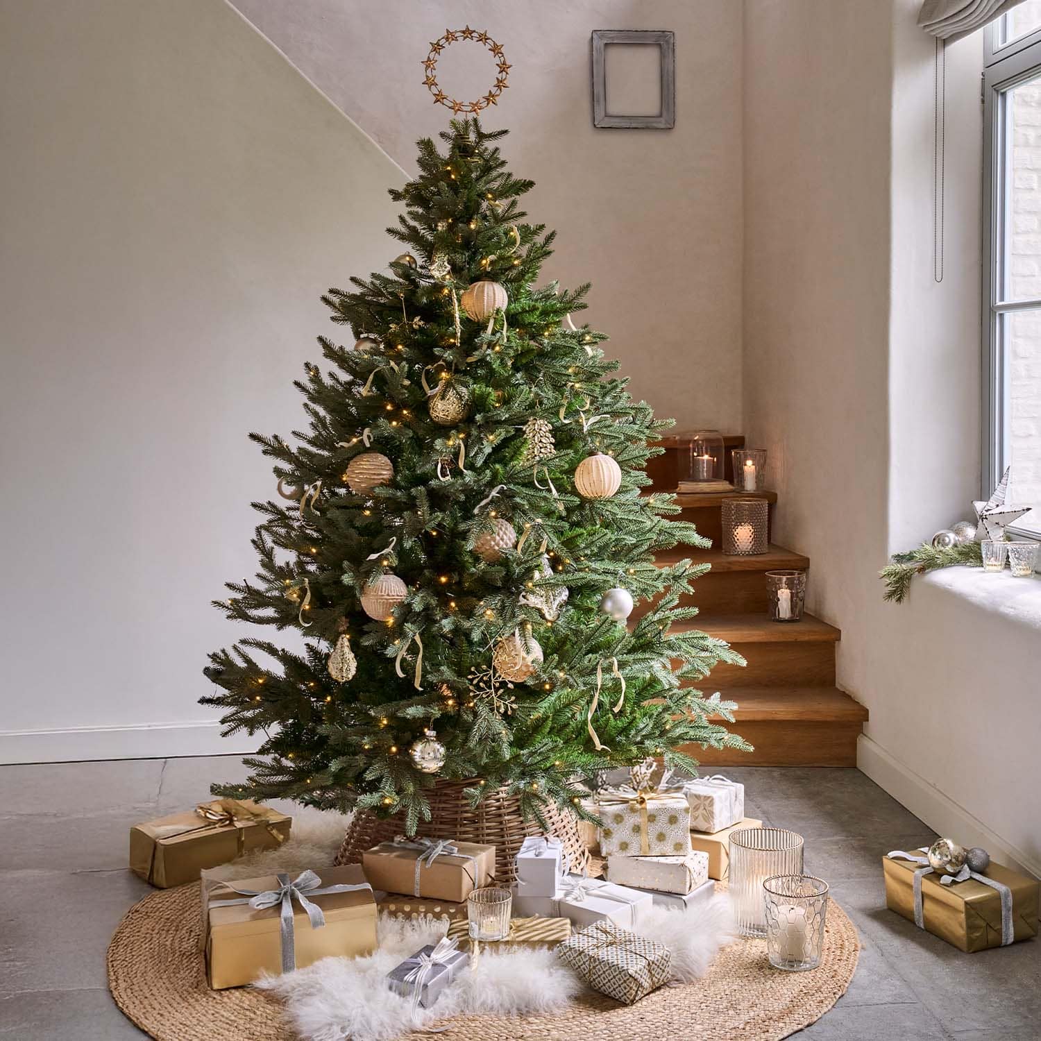 Groene kerstboom met natuurlijke versieringen en gouden cadeaus op ronde mat in lichte kamer