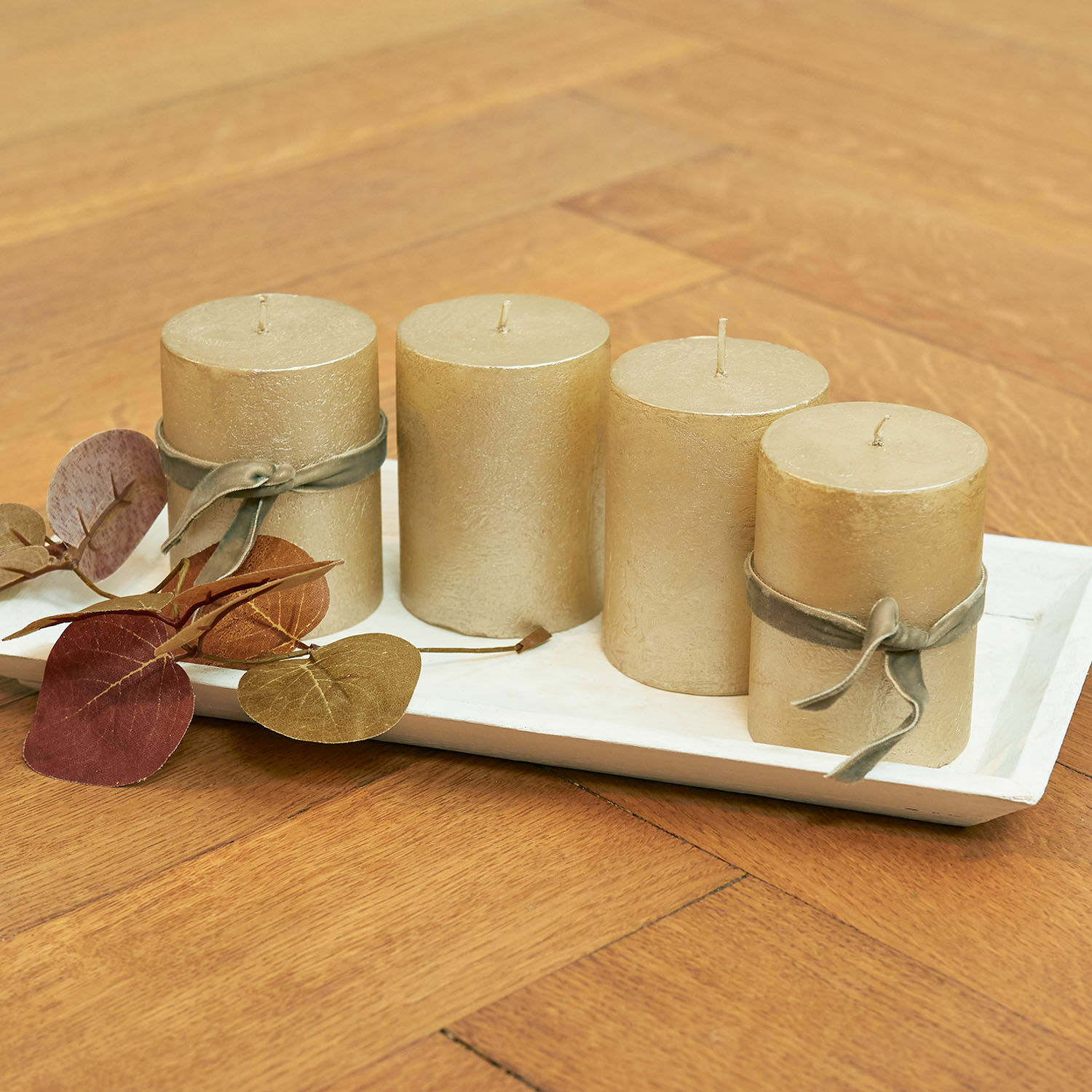 Kaars set van 4 Virrans Set van vier gouden decoratieve kaarsen op een wit dienblad met decoratieve bladeren op houten tafel