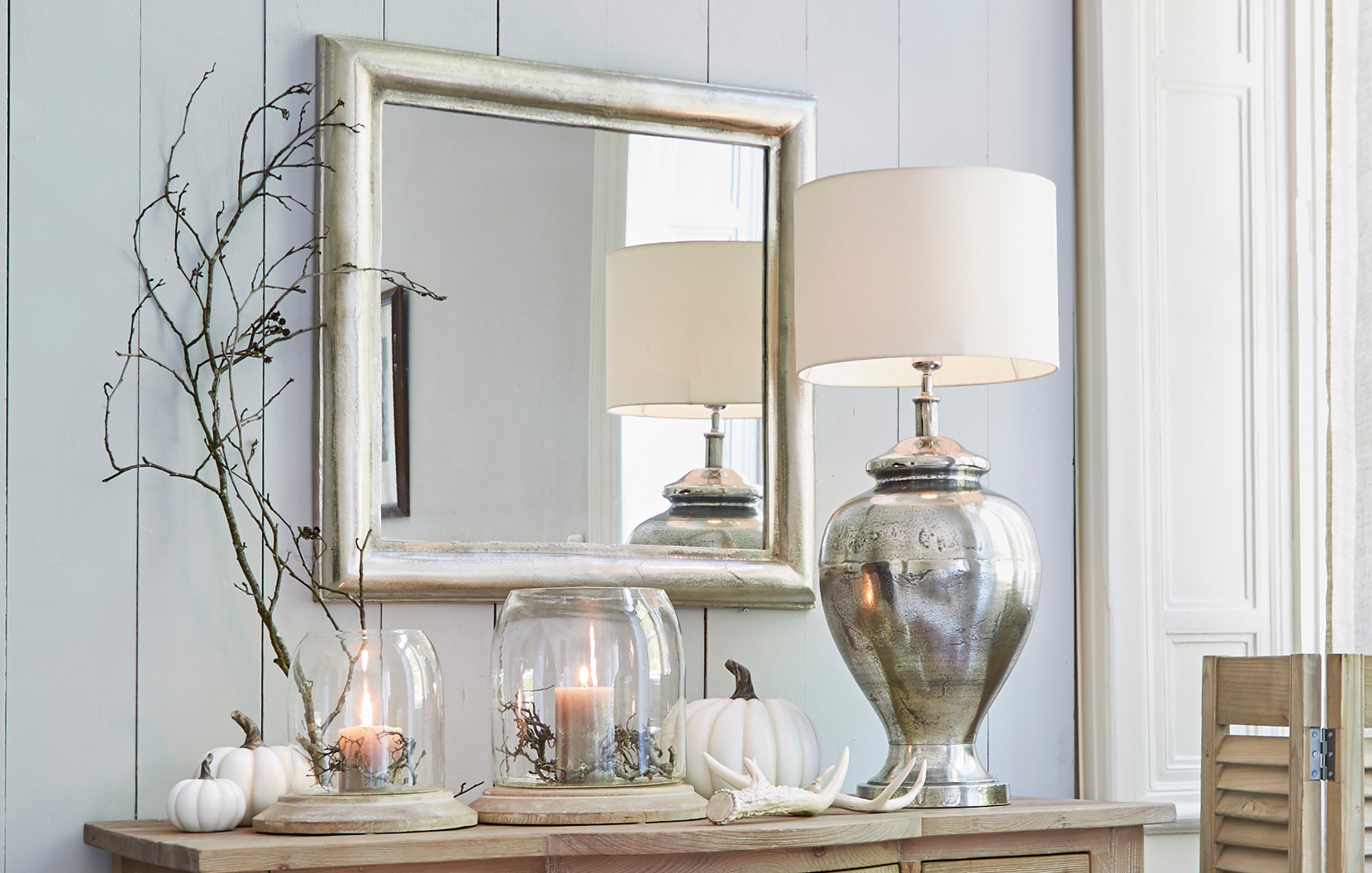 Klassiek elegant interieur met zilveren spiegel, metalen lamp en decoraties op houten kast