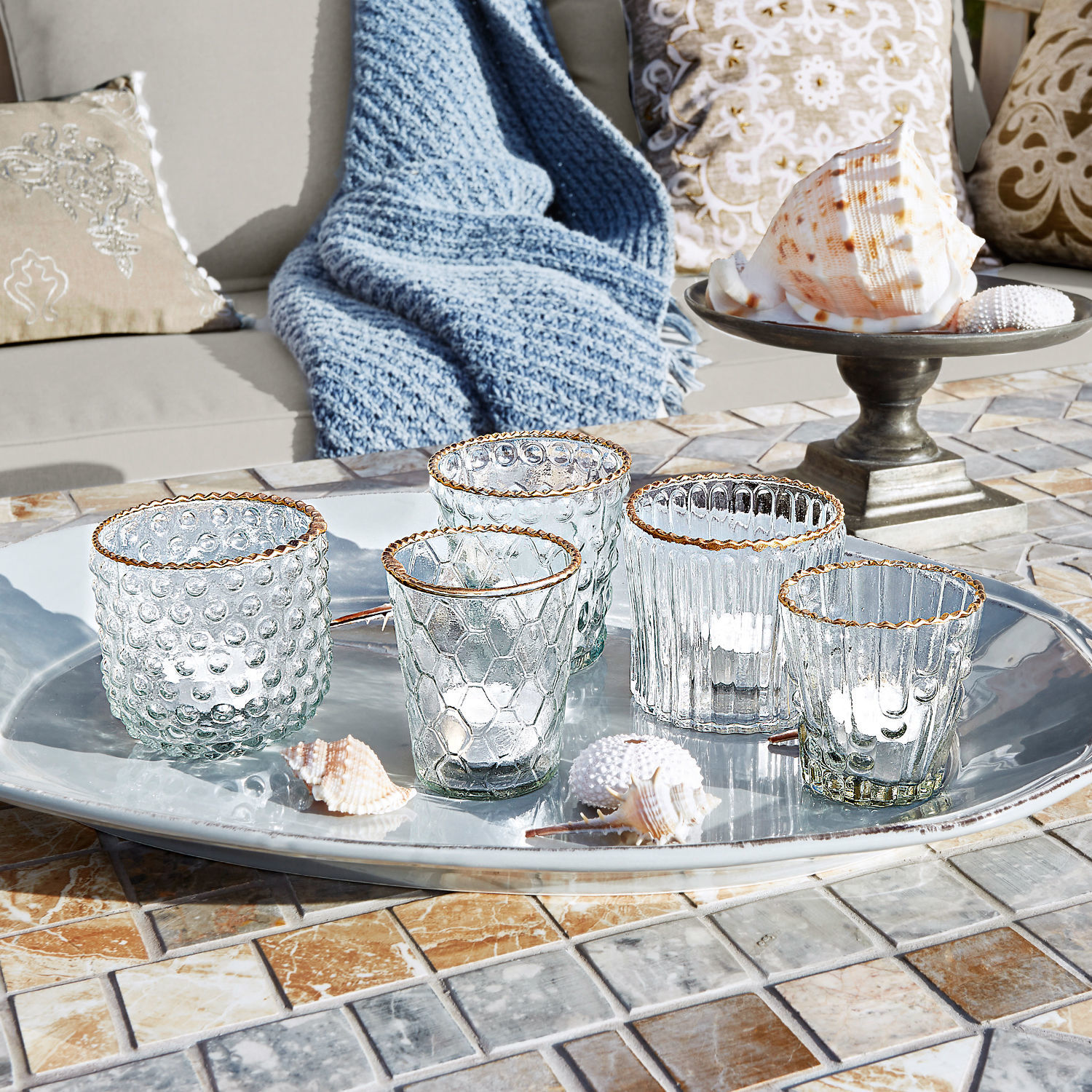 Set van vijf glazen theelichthouders met gouden rand op zilveren dienblad op mozaïektablet