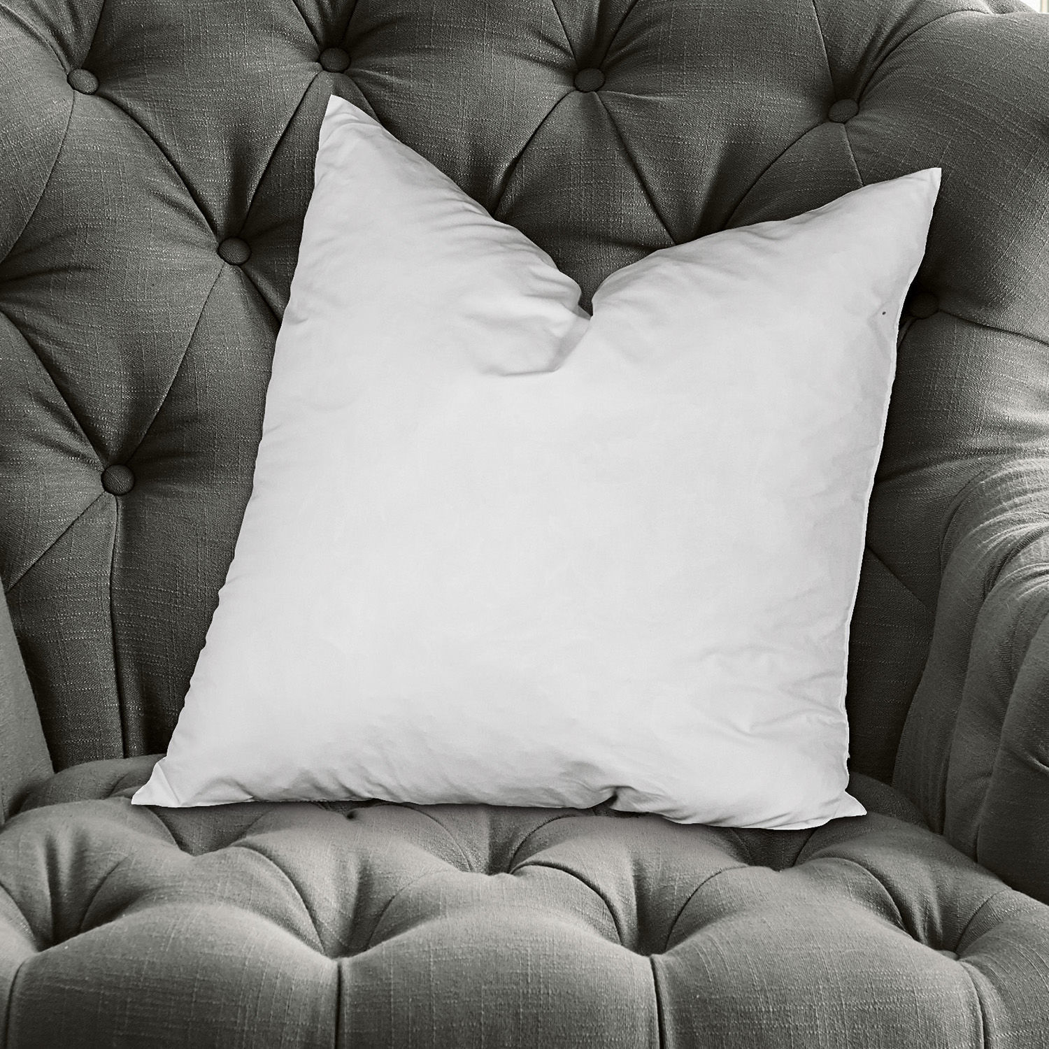 Kussenvulling Indra Witte sierkussen op grijze gestoffeerde stoffen fauteuil, comfortabele woonaccessoire