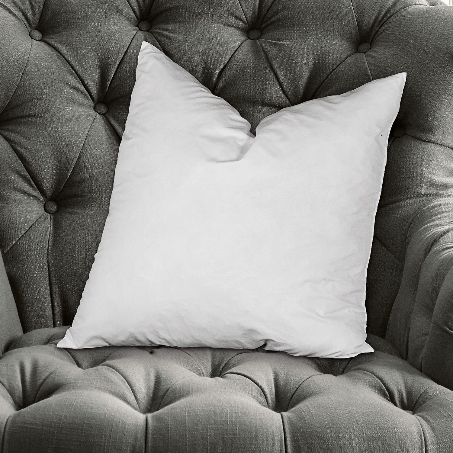 Kussenvulling Indra Witte sierkussen op grijze gestoffeerde stoffen fauteuil, comfortabele woonaccessoire