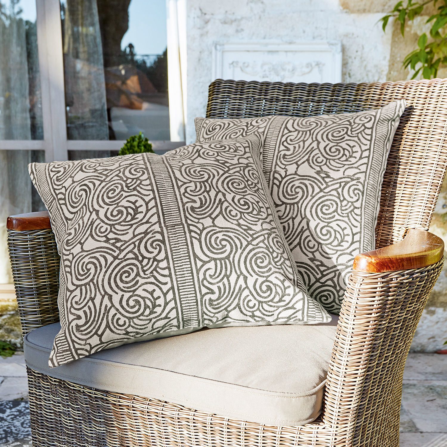 Kussenhoes set van 2 Ensis Twee decoratieve katoenen kussens in beige met bruin patroon op rotan stoel op terras
