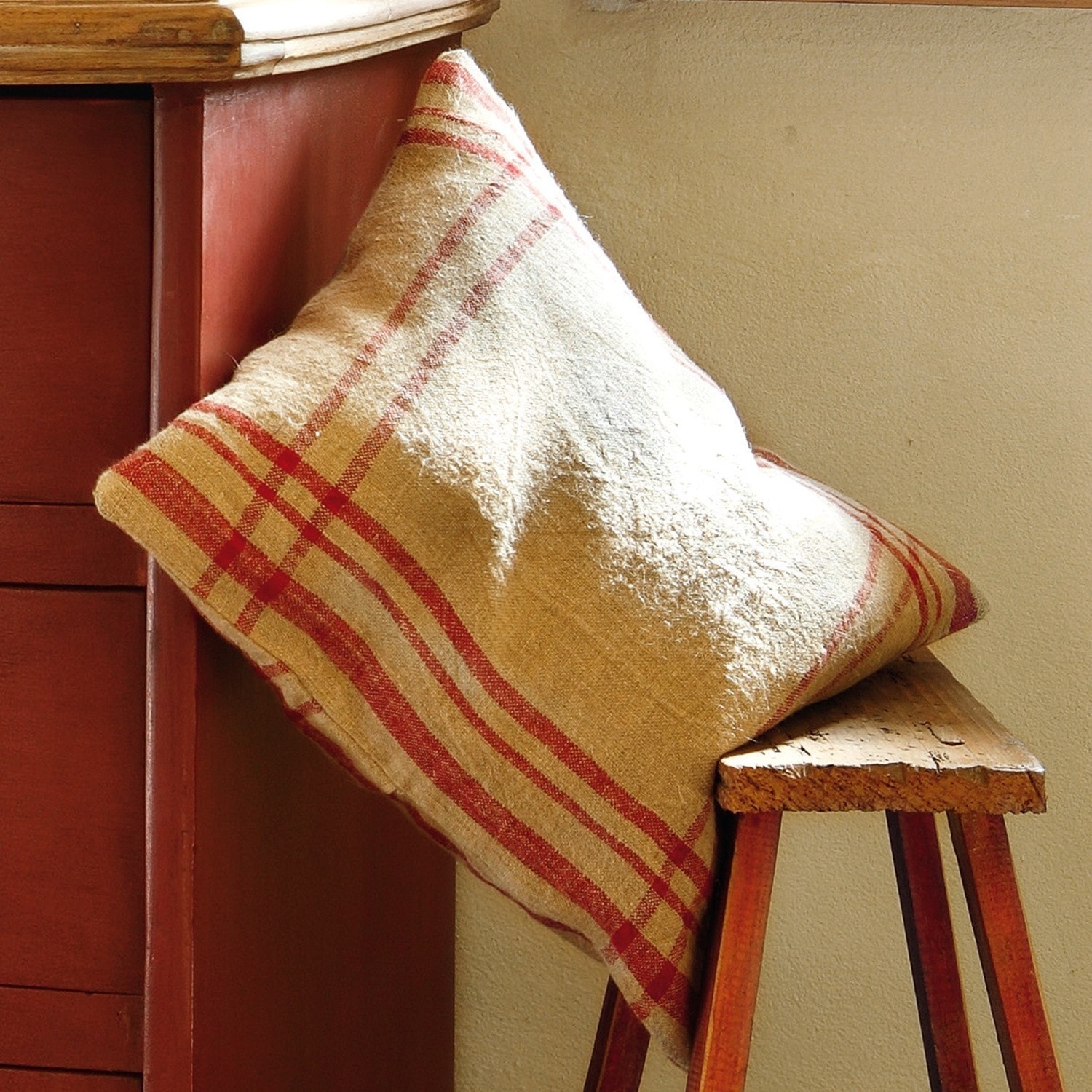 Kussenhoes Damian Beige kussen met rood ruitpatroon op houten bank, sfeervolle interieurdecoratie