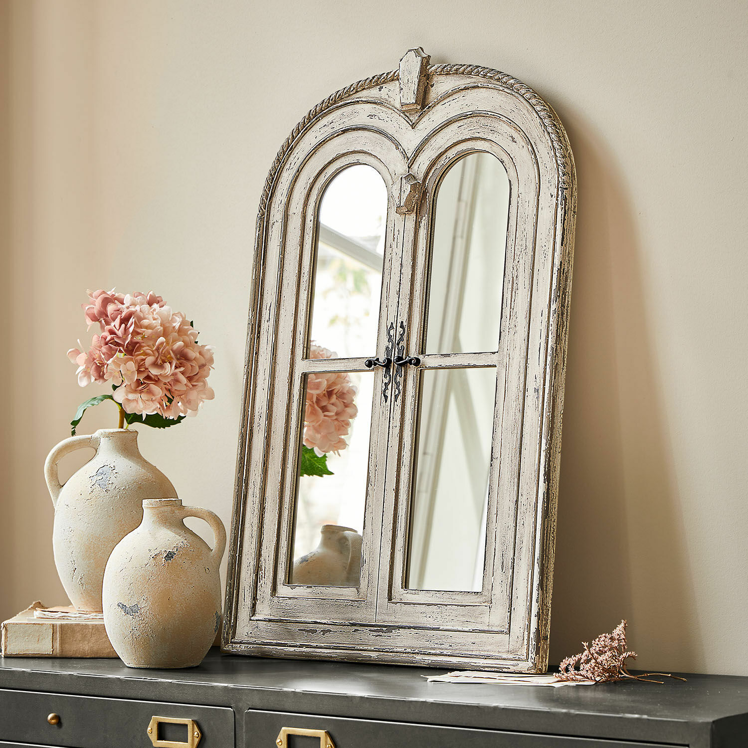 Rustieke houten spiegel in wit verweerd op zwarte kast met roze bloemen decoratie