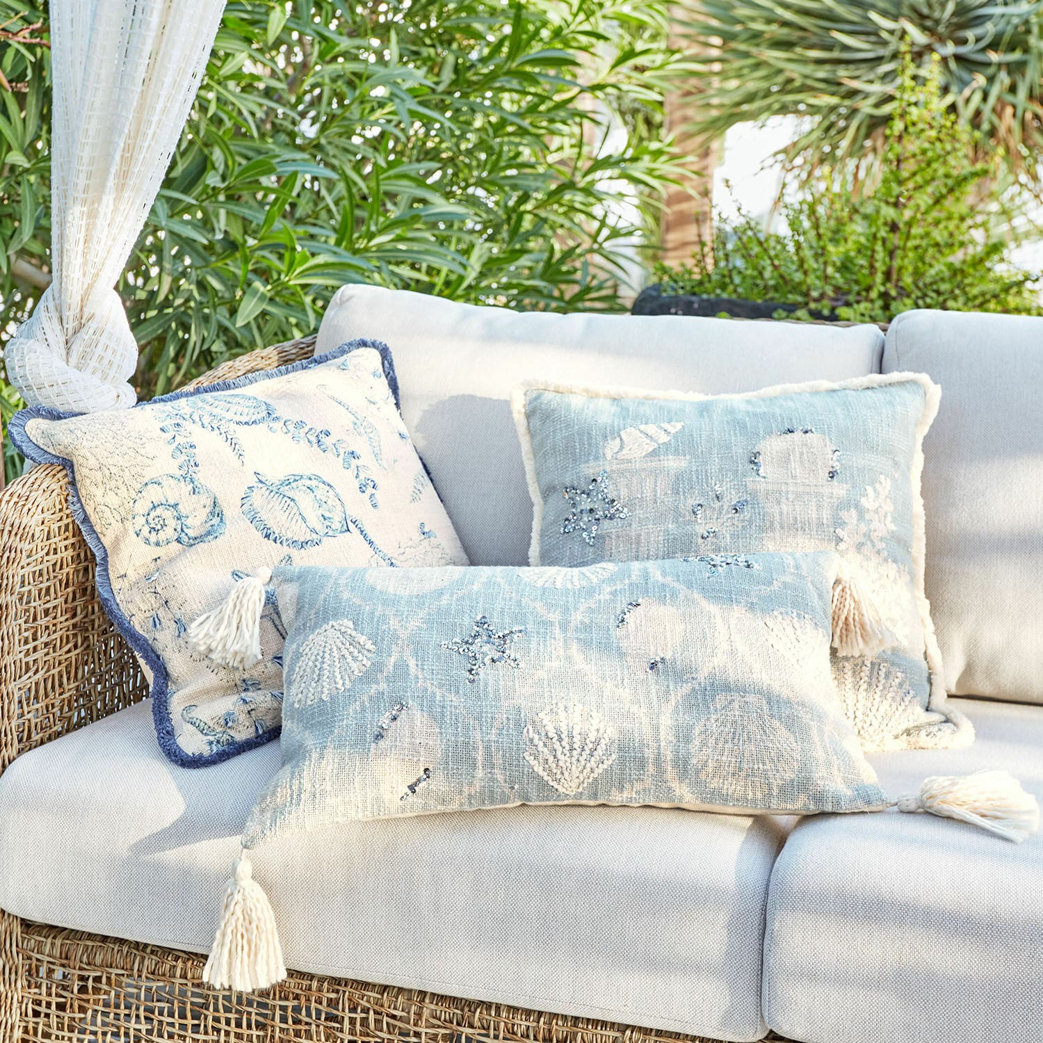 Kussenhoes set van 3 Calerand Set decoratieve kussens met schelpen- en zeesterrenmotief in blauw- en beigetinten op rotanbank