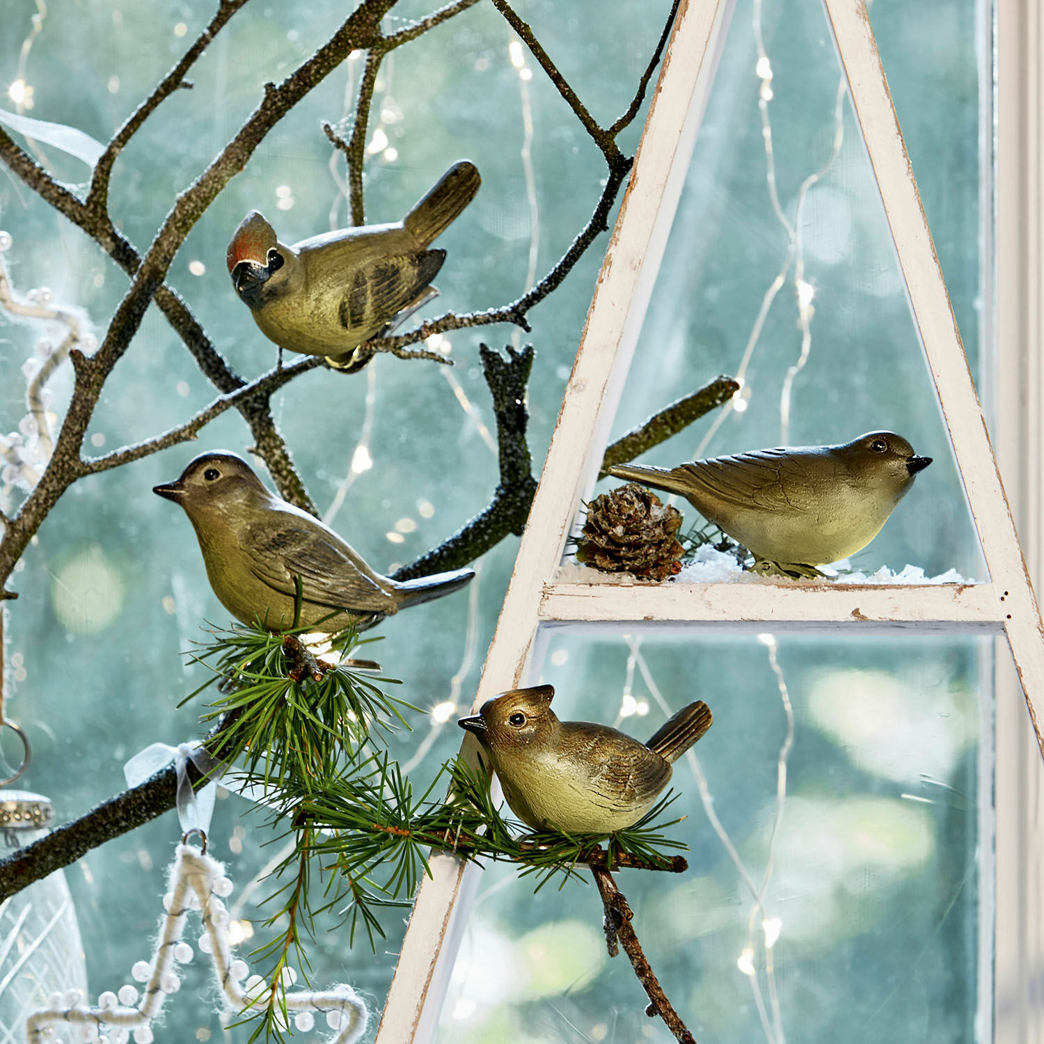 Vogel set van 4 Pompaire Decoratieve kunststof vogels op takken en wit houten frame bij raam met LED-lichtjes