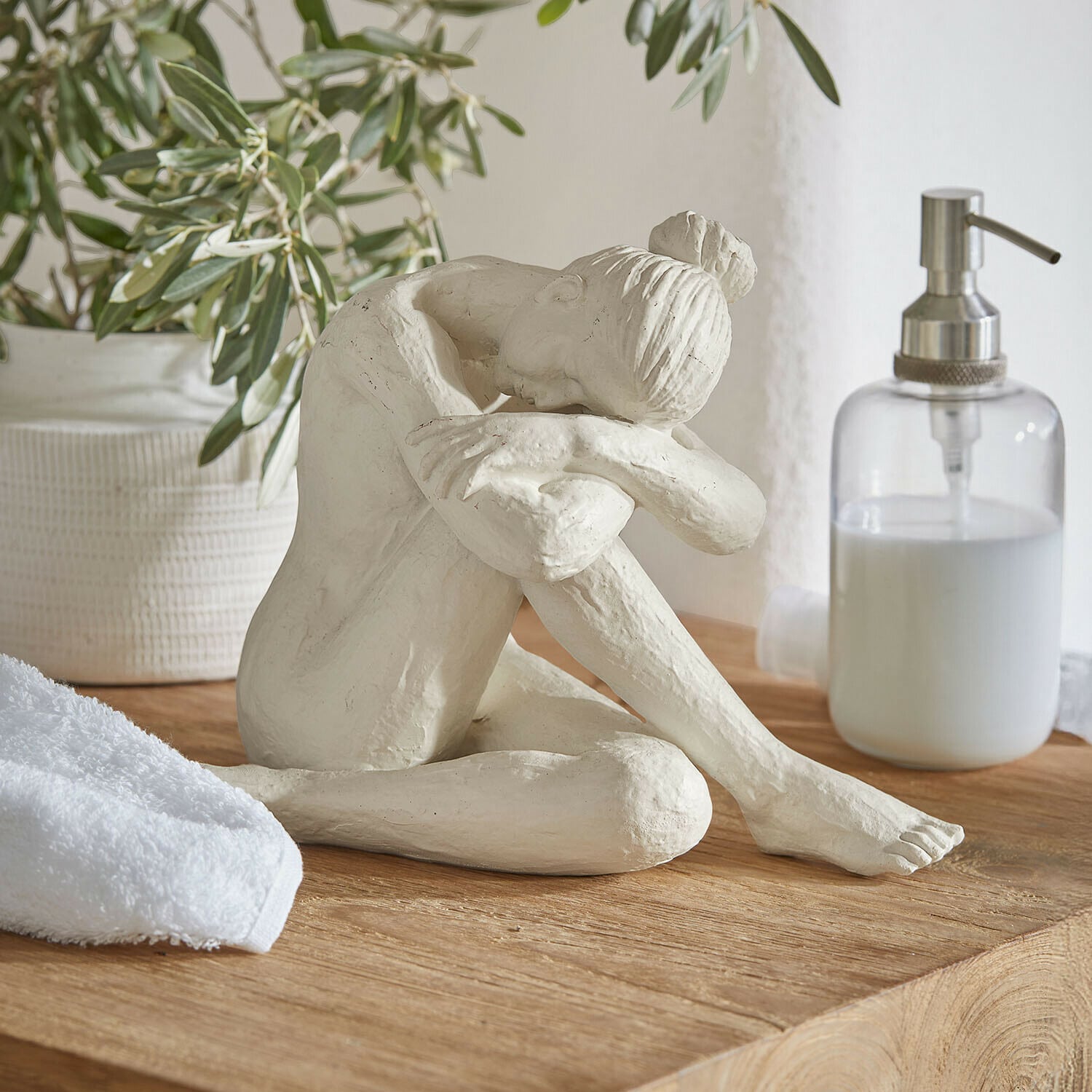 Beeldje Savigné Witte sculptuur van zittende vrouw met hoofd op gebogen knieën op houten blad in badkamer