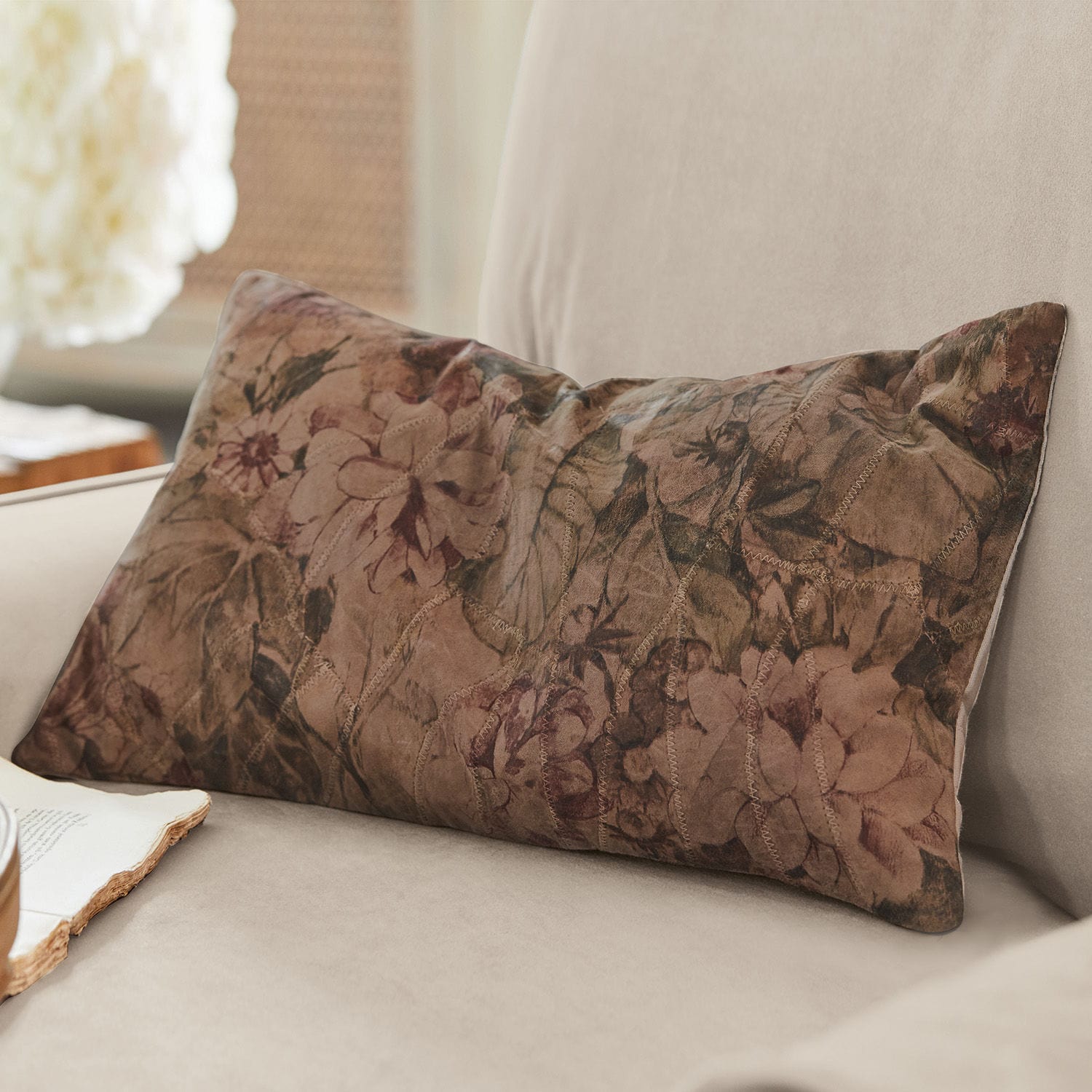 Decoratief kussen van zacht materiaal met bruin bloemenpatroon op beige bank