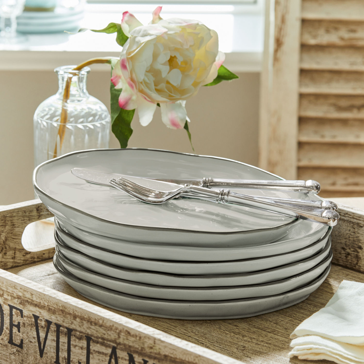 Set grijze keramische borden op houten dienblad met mes en vork, tafeldecoratie