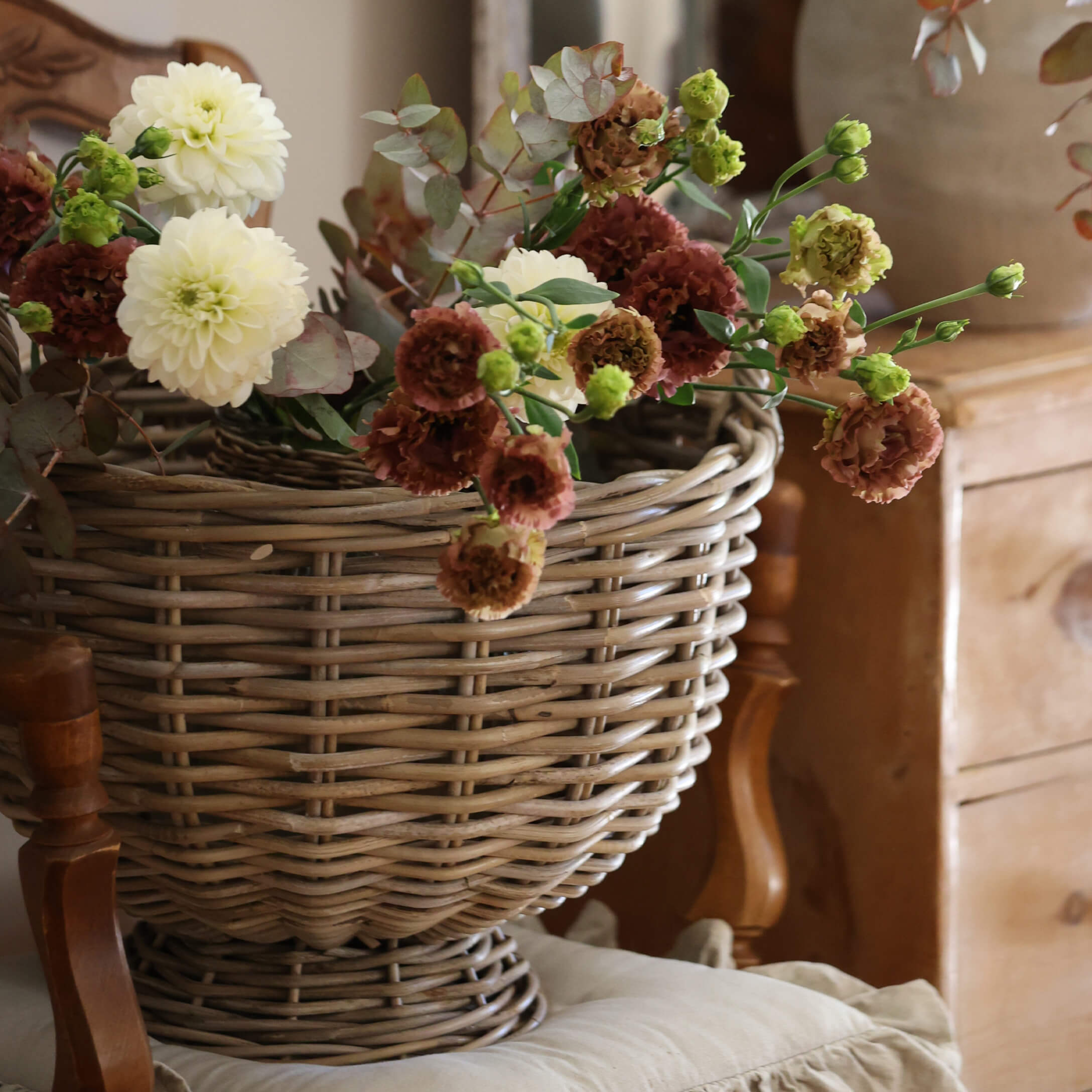 Decoratieve rieten mand met crème en bruine bloemen voor vintage interieur