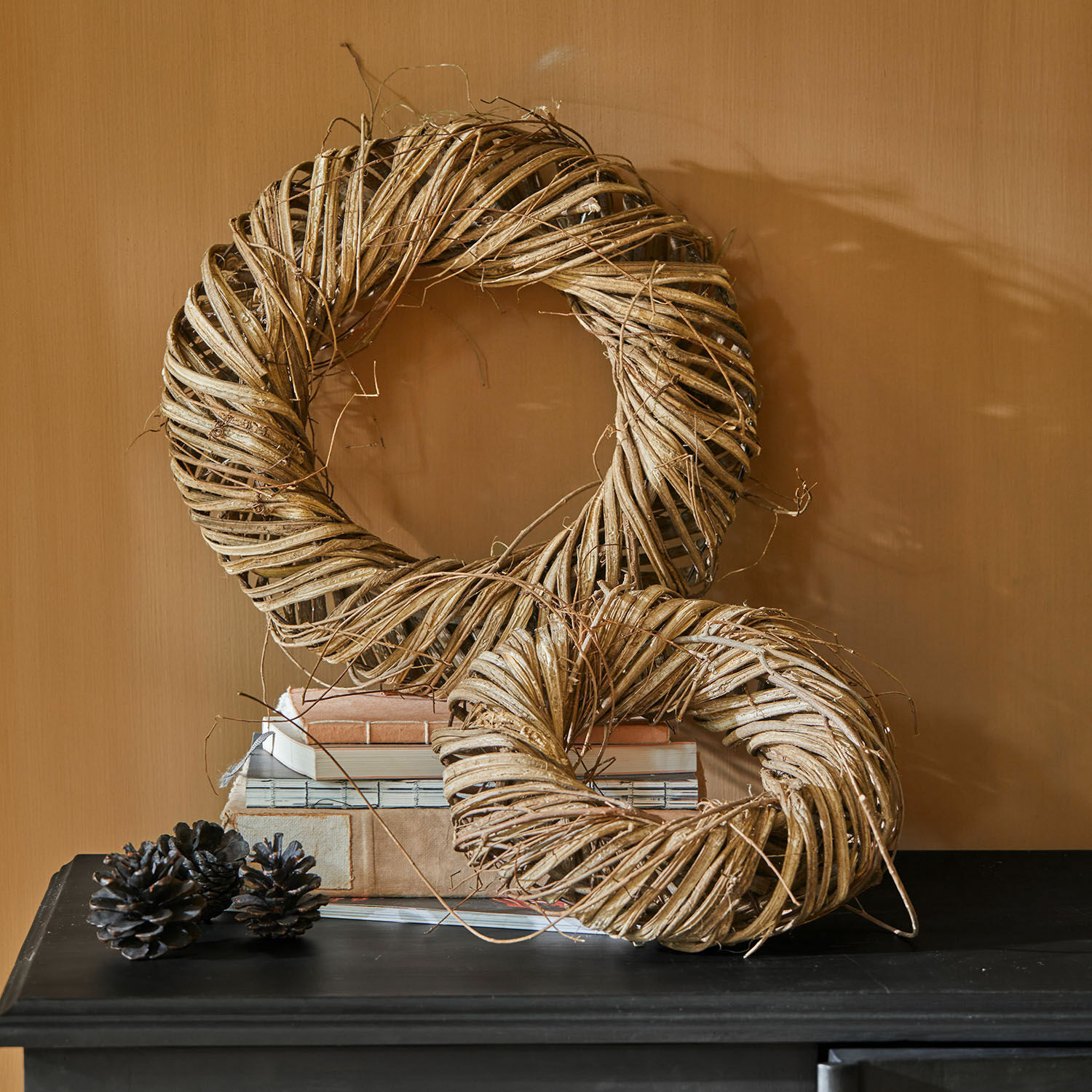 Decoratieve kransen van natuurlijk beige wilgenmateriaal op een zwarte tafel met boeken